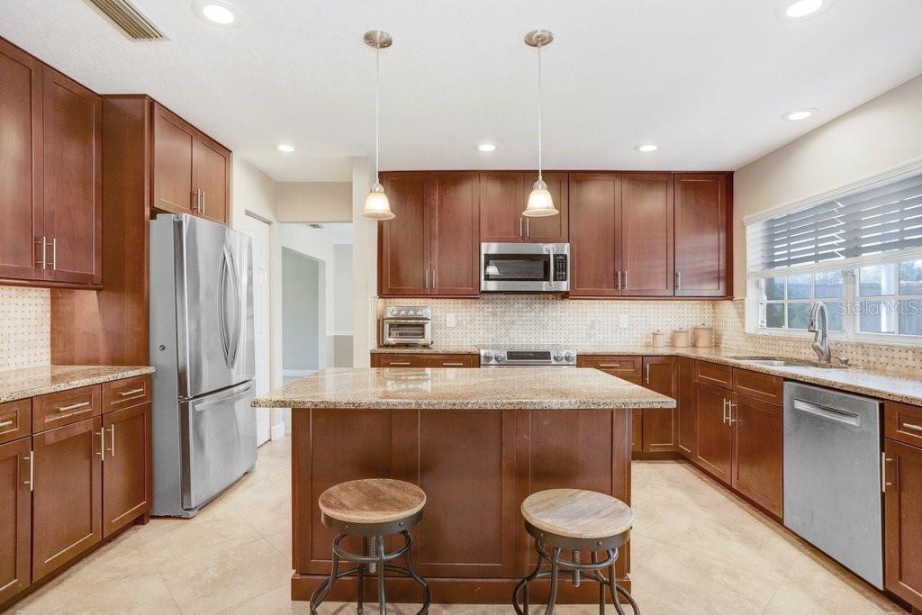 Beautiful kitchen with new cabinets, backsplash, wine refrigerator, granite countertops, and stainless steel appliances