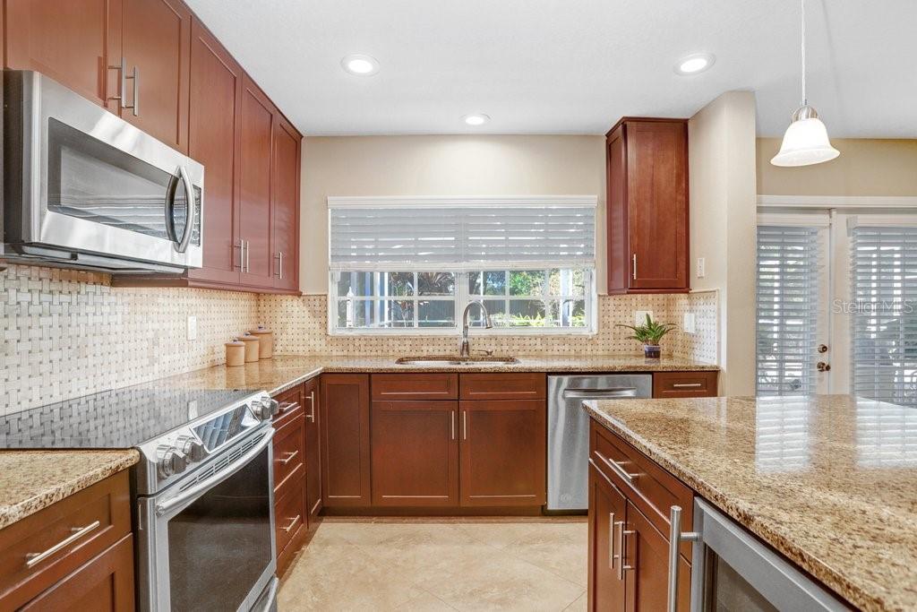 Beautiful kitchen with new cabinets, backsplash, wine refrigerator, granite countertops, and stainless steel appliances