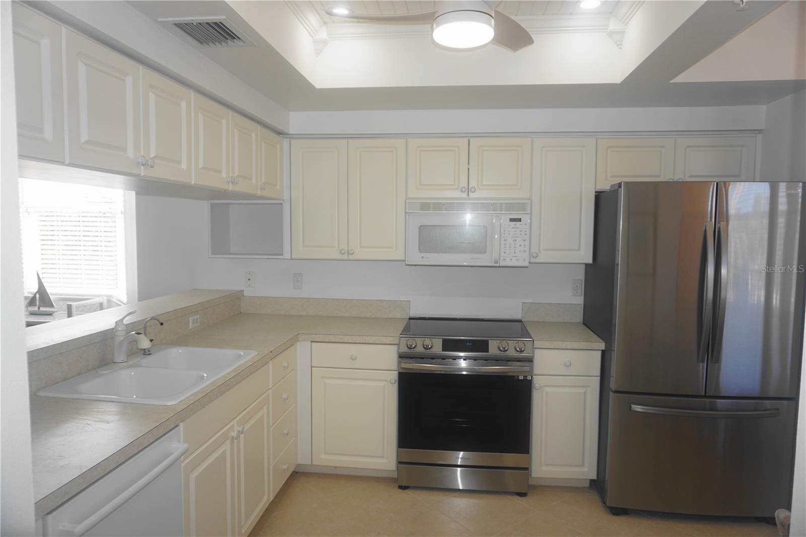 Light, bright kitchen features stainless steel appliances.