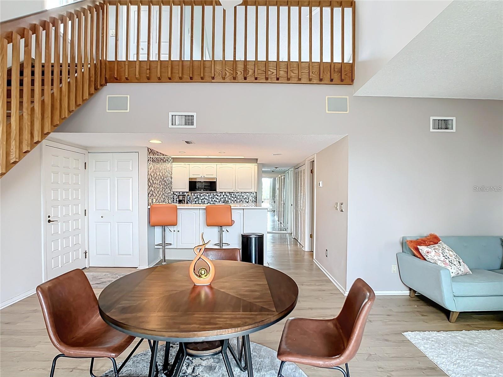 The soaring ceilings, open floor plan, and striking wood staircase combine to create a dramatic, awe-inspiring atmosphere.