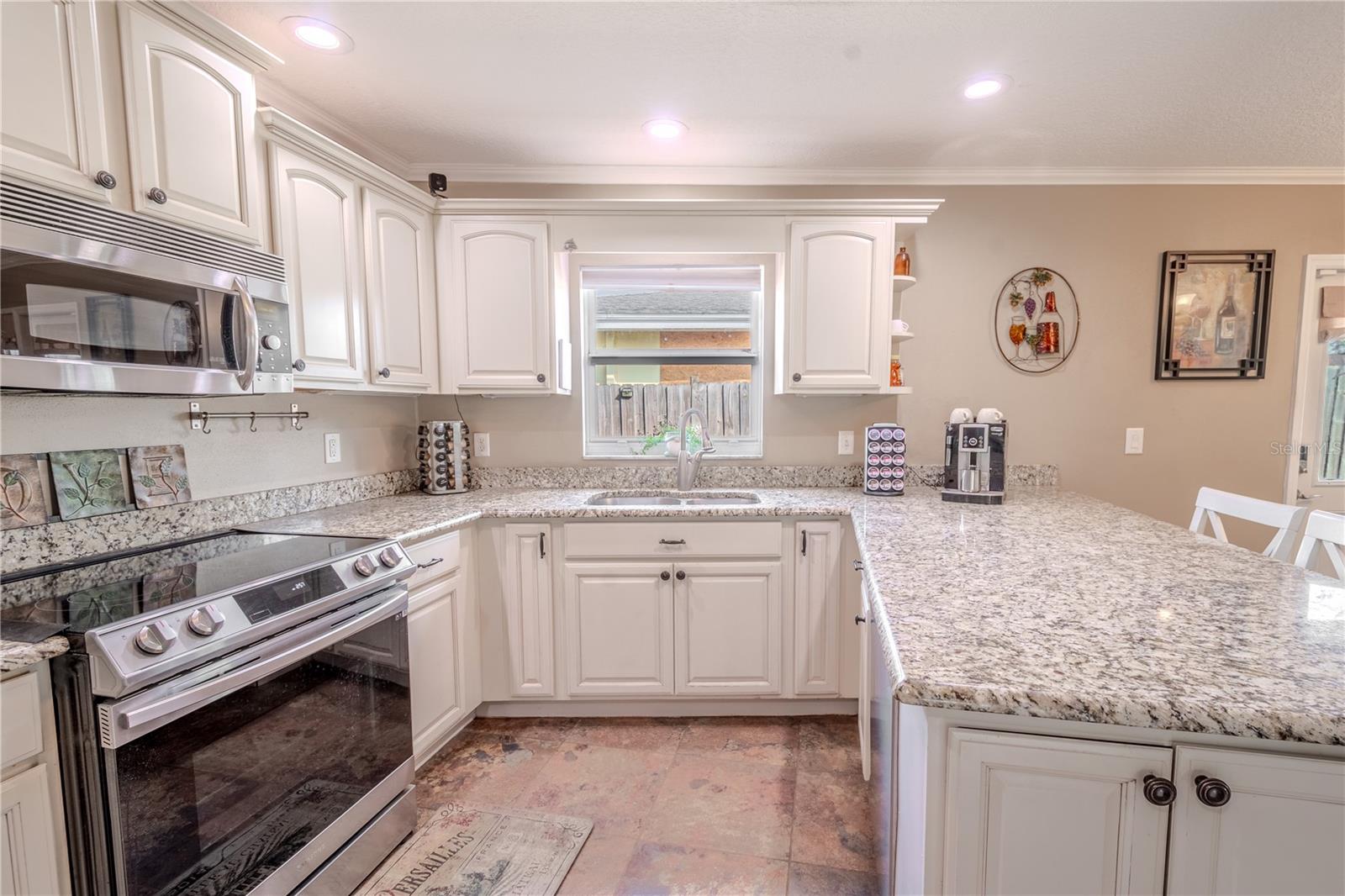 The kitchen features a stainless steel double basin sink beneath a window with a view of the back yard.