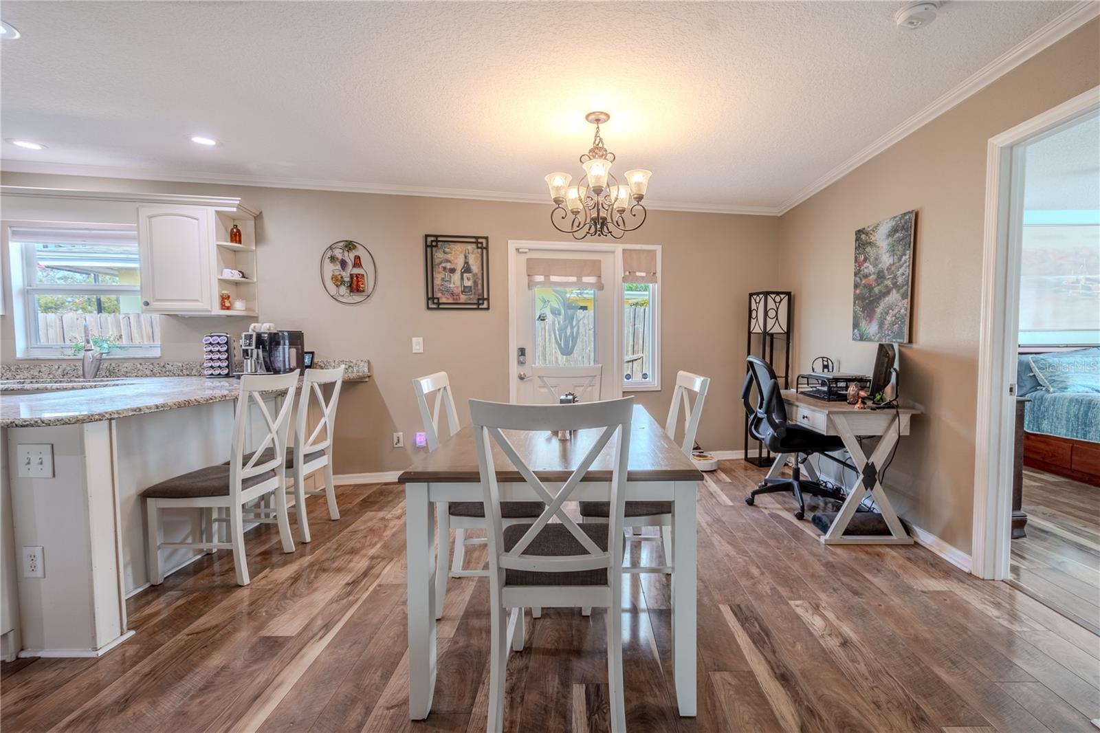 The kitchen is opposite the dining room  which features a six-globe chandelier, crown molding and wood flooring.