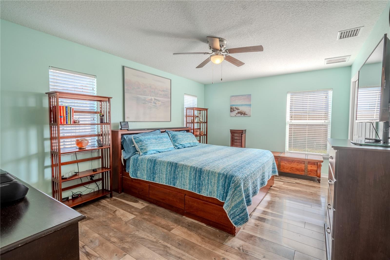 The primary bedroom features wood flooring, a ceiling fan with light kit, a walk-in closet and an ensuite bath.