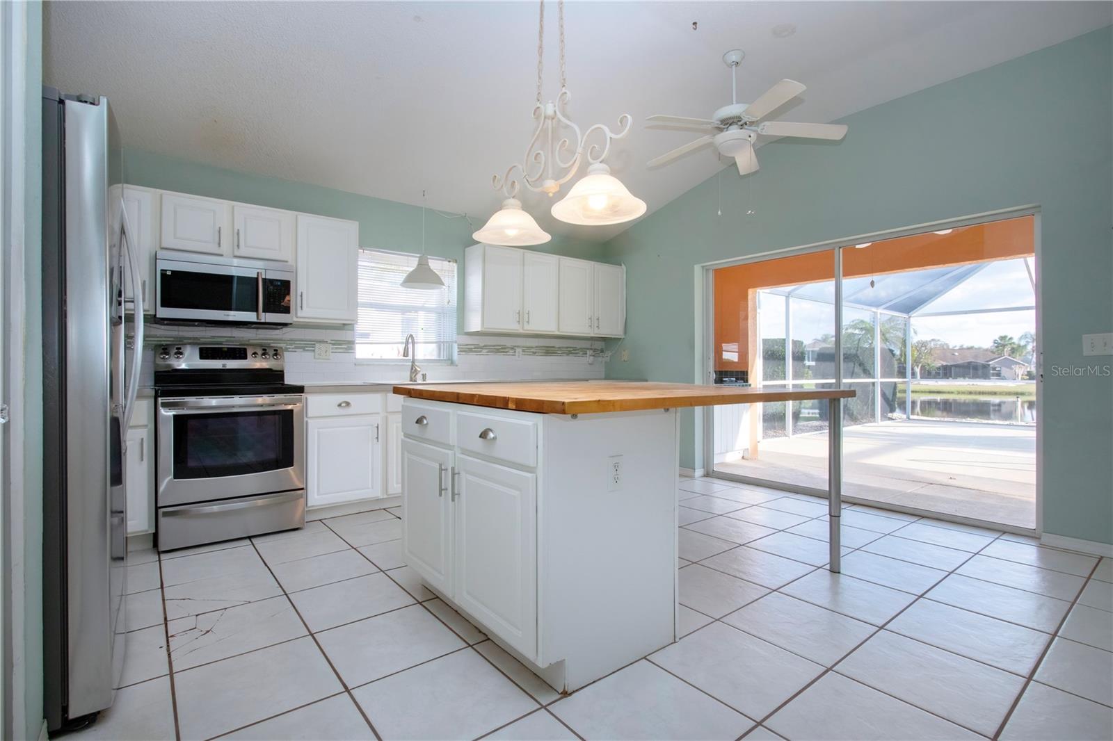 Kitchen w/Stainless appliances, Island w/Work table and entrance to pool area