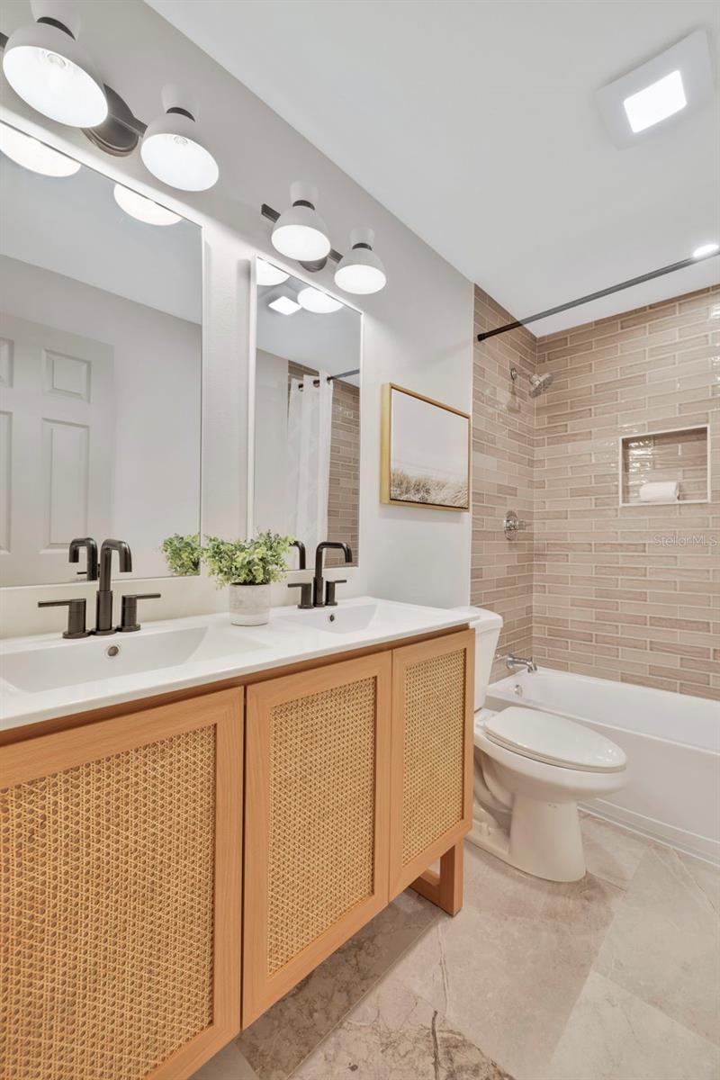 Bathroom with double sink vanity and gleaming tile tub/shower combo