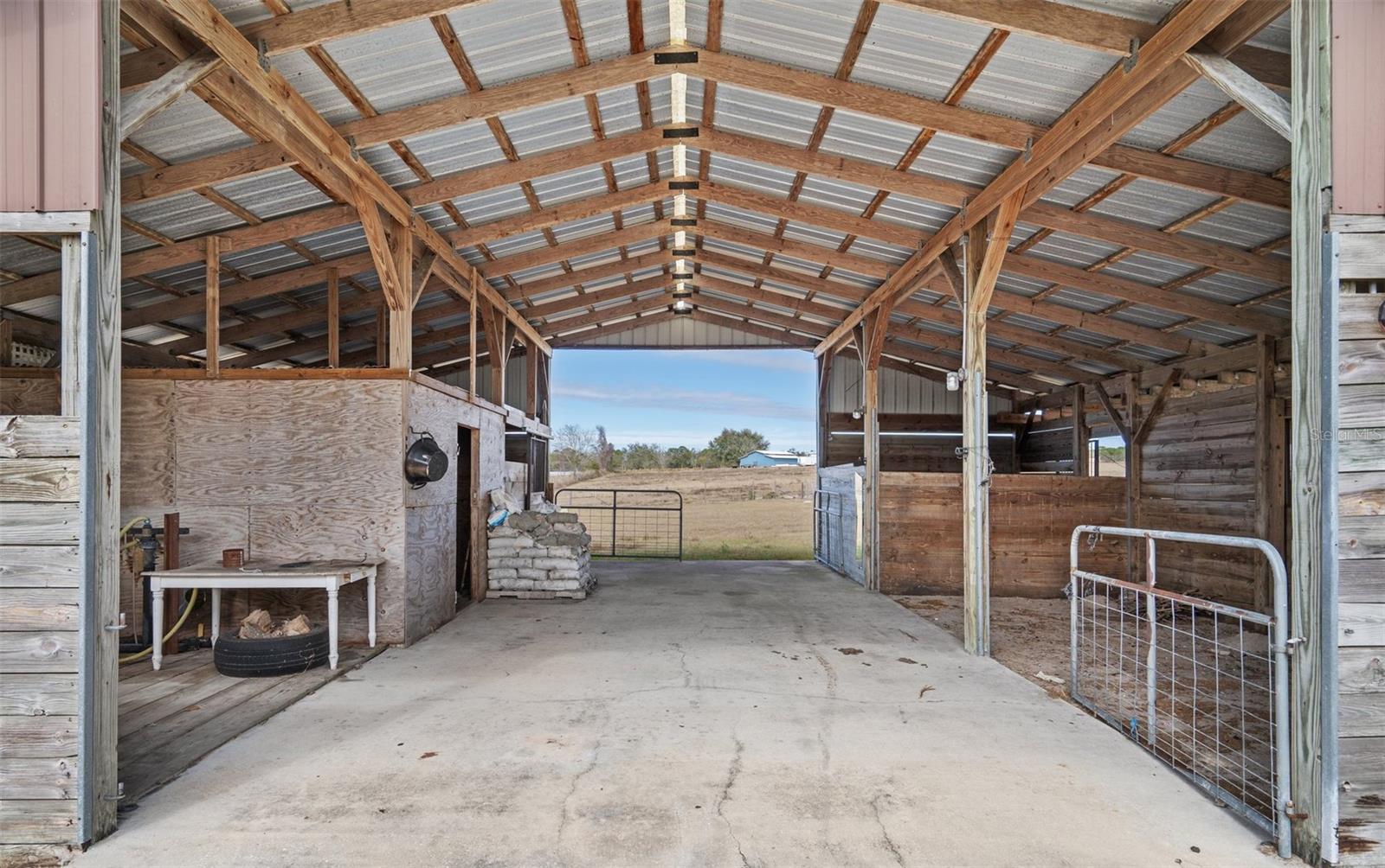 Center-aisle barn with concrete center aisle, stalls, and tack/feed room.