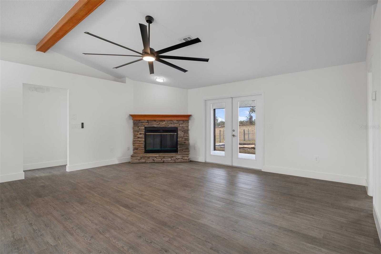 Great room with wood beam accent ceiling and stone fireplace