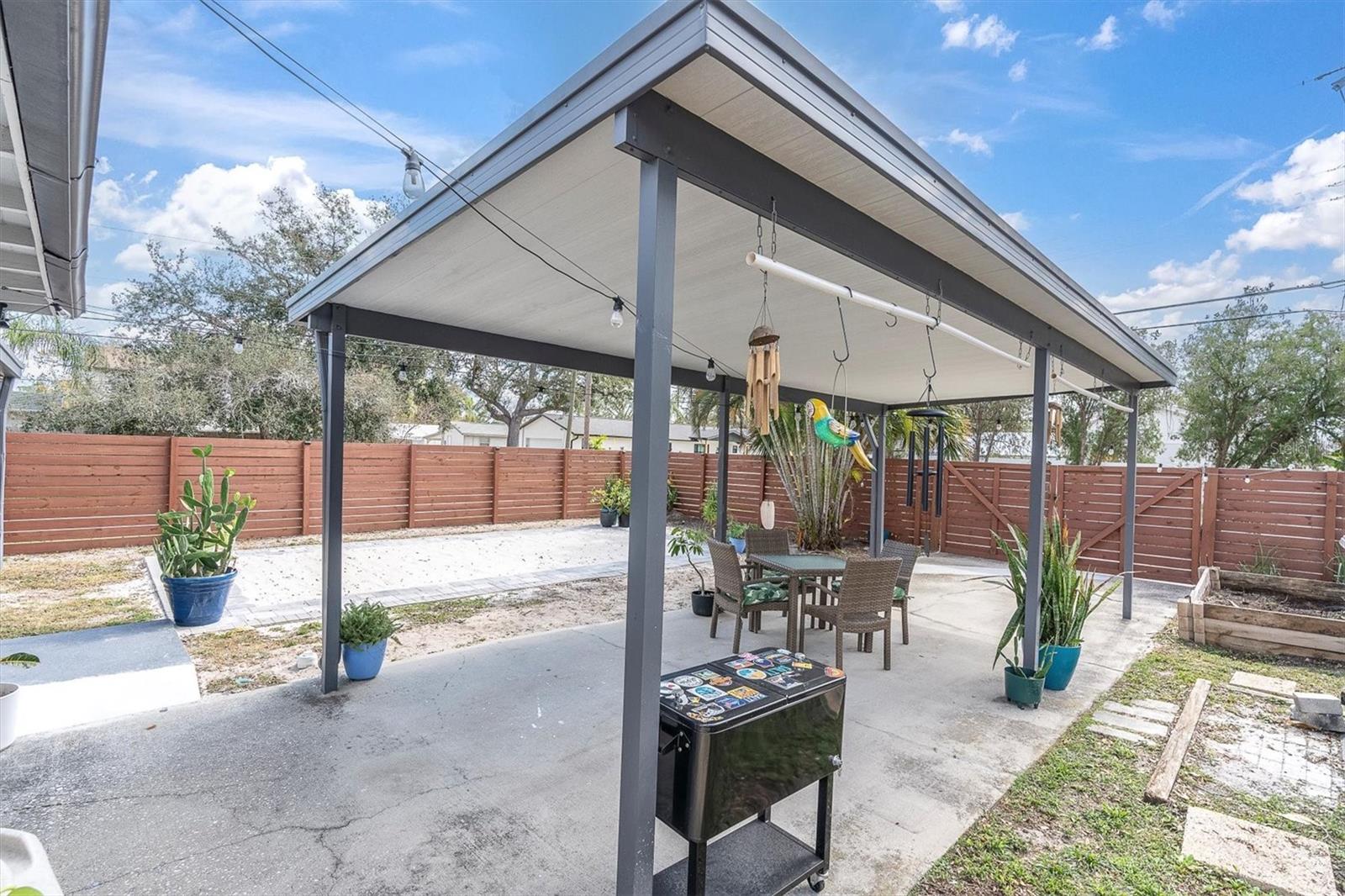 Spectacular backyard for entertaining, with privacy fence with gated entrance, covered carport for two cars.  Sandy area for soaking up the Florida sun or playing volleyball, corn hole, or the outdooor game of your choice.