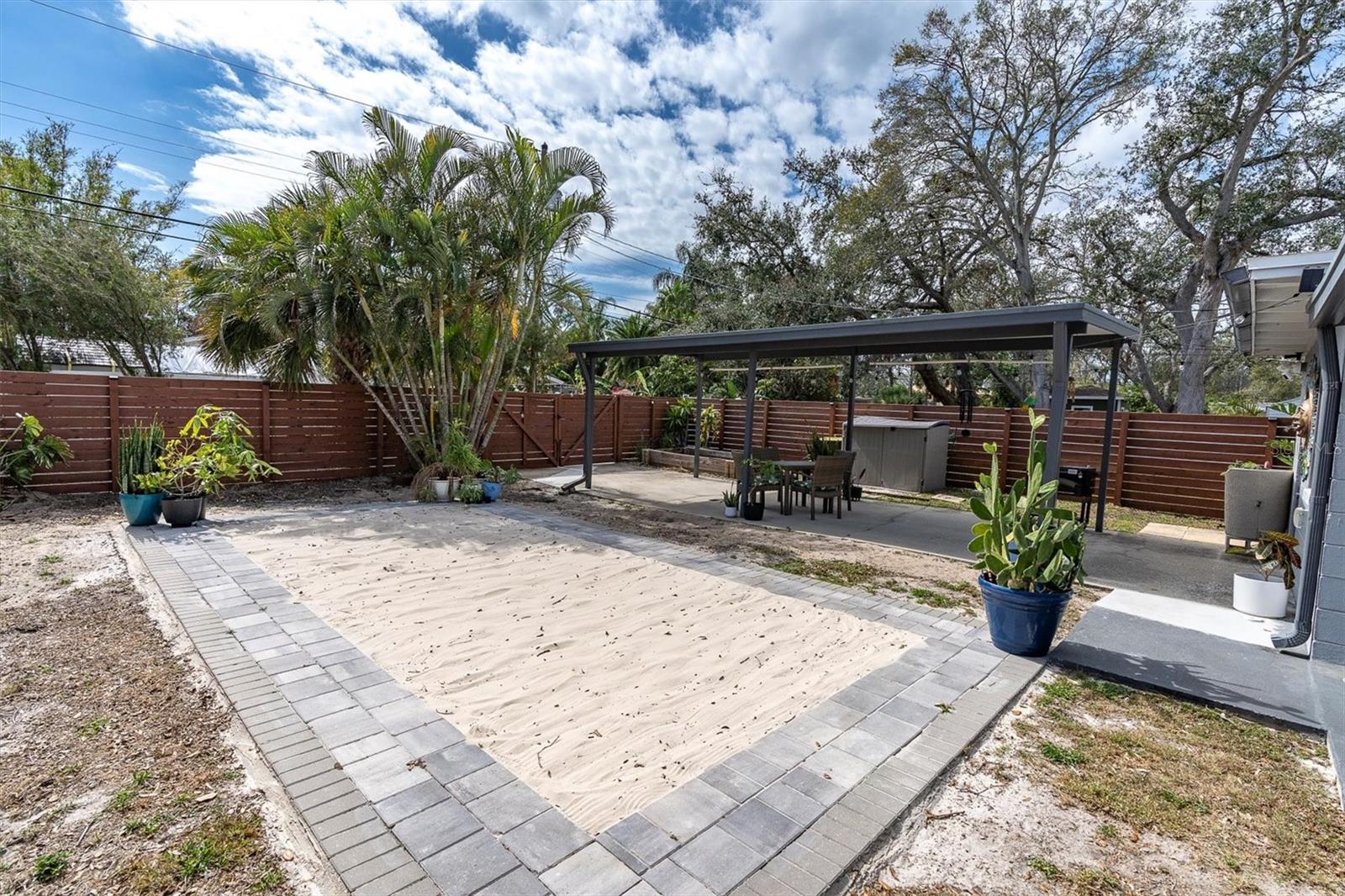 Spectacular backyard for entertaining, with privacy fence with gated entrance, covered carport for two cars.  Sandy area for soaking up the Florida sun or playing volleyball, corn hole, or the outdooor game of your choice.