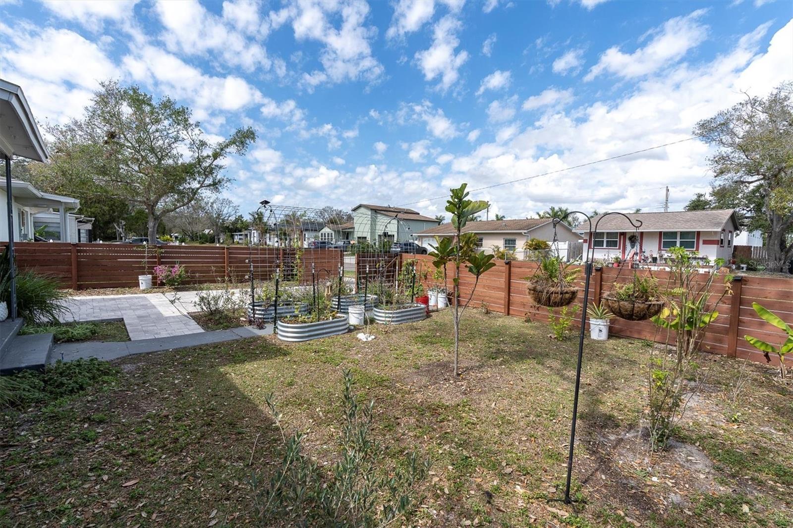 Mature landscaped in front yard with brick paved driveway, fenced and gated.