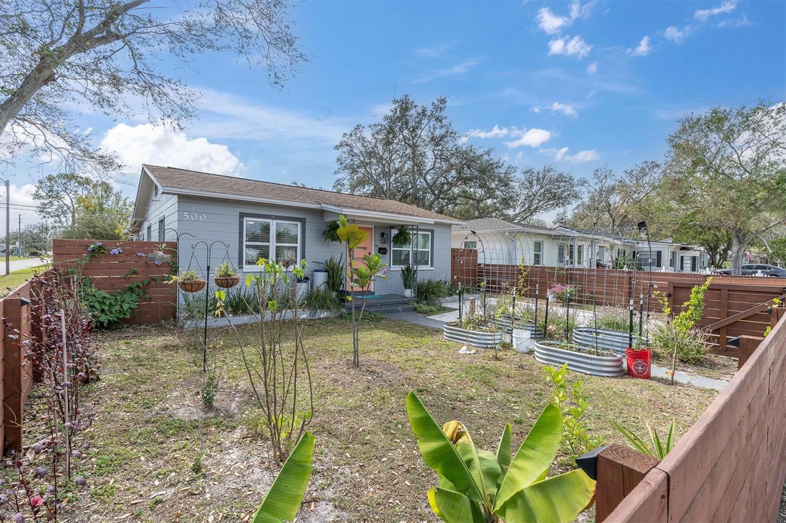 Mature landscaped in front yard with brick paved driveway, fenced and gated.