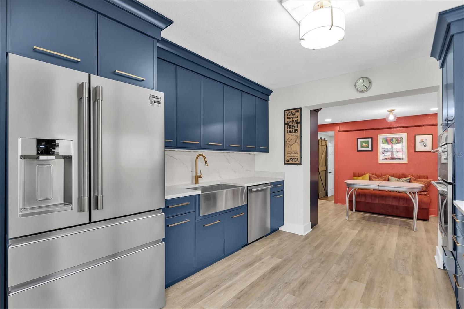 New stainless steel appliances, including a counter-depth refrigerator with convertible freezers, a wall oven/microwave combo with air fryer, a dishwasher conveniently located next to the large one bowl sink with touchless smart kitchen faucet, and a 36" induction cooktop with external downdraft. Gorgeous solid quartz countertops and seamless Mother of Pearl backsplash perfectly complement the blue wood cabinets.