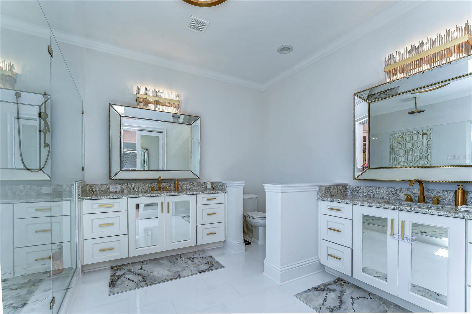 Indulge in opulence with this bathroom's lavish dual vanities, gilded accents, and exquisite flooring.