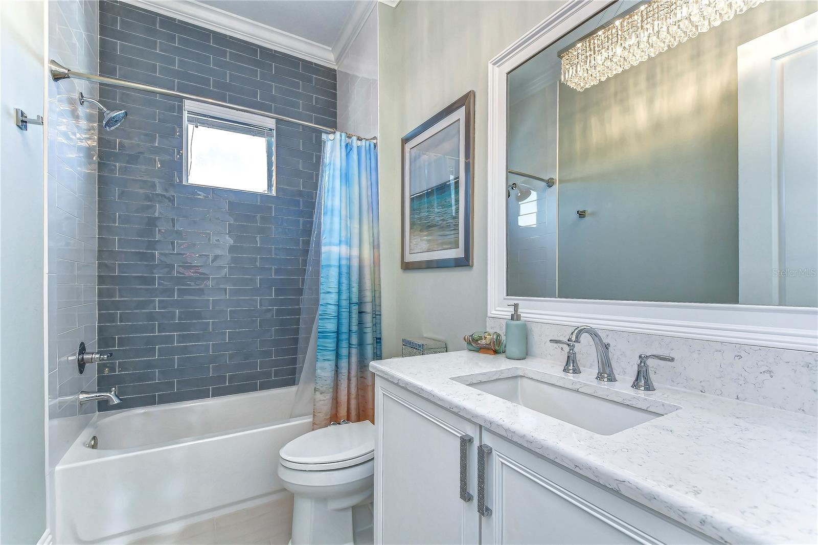 Immerse yourself in this lavish third bathroom retreat, featuring sleek gray brick tiles and an elegant vanity.