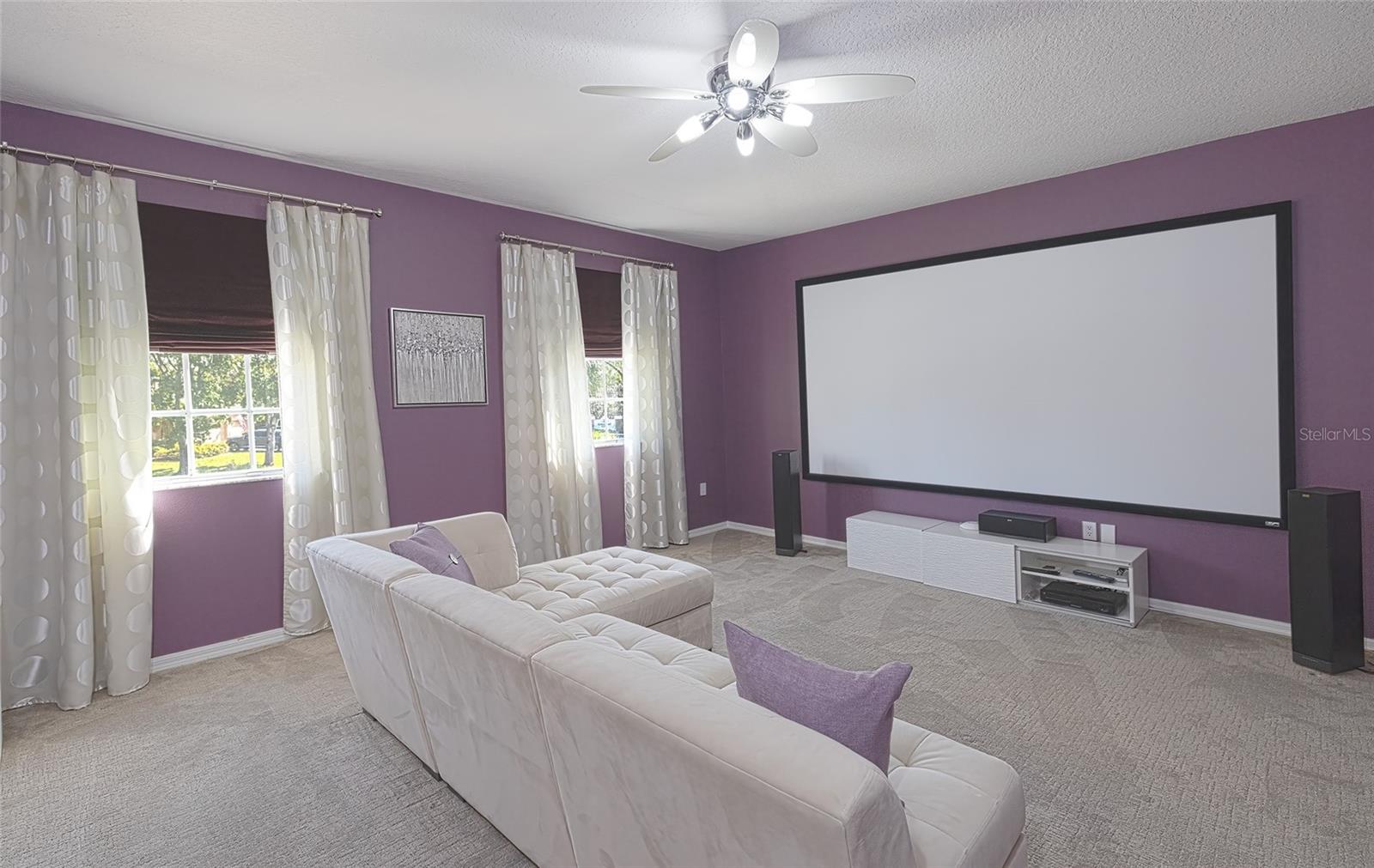 Media room features a projection screen, black out roman shades & designer ceiling fan.