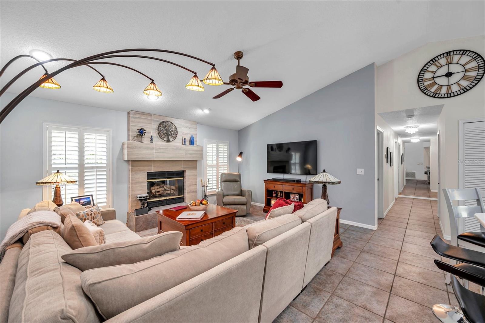 The family room features a wood burning fireplace, vaulted ceiling and plantation shutters.