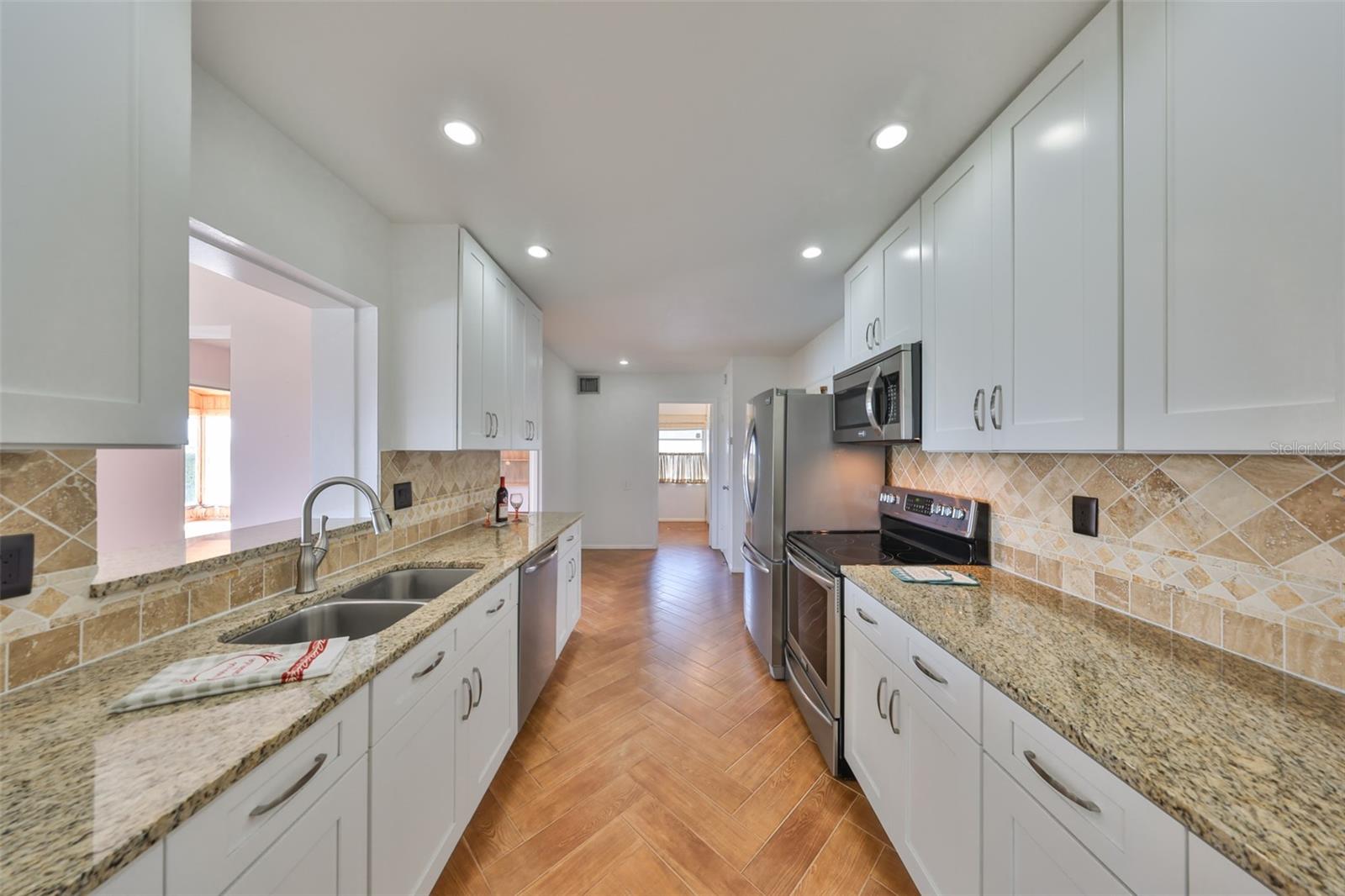 Beautifully updated kitchen with granite counters, stainless appliances and Herringbone wood looking tile flooring.