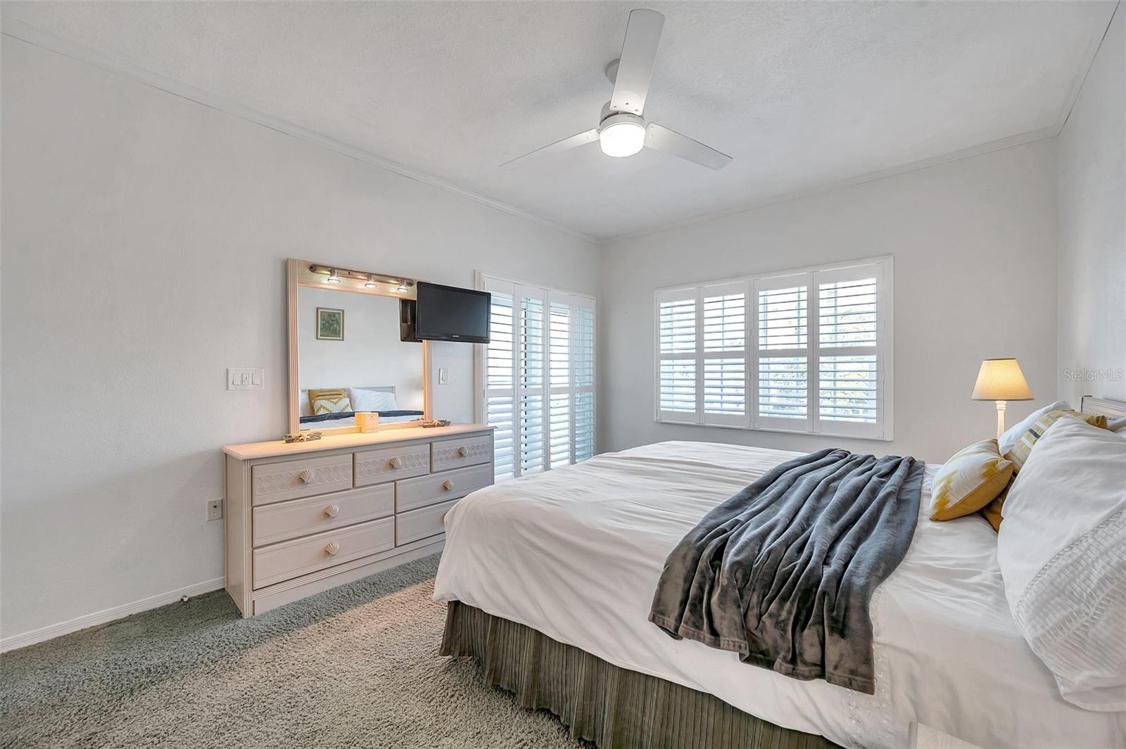 The primary bedroom features sliders to the balcony and plantation shutters