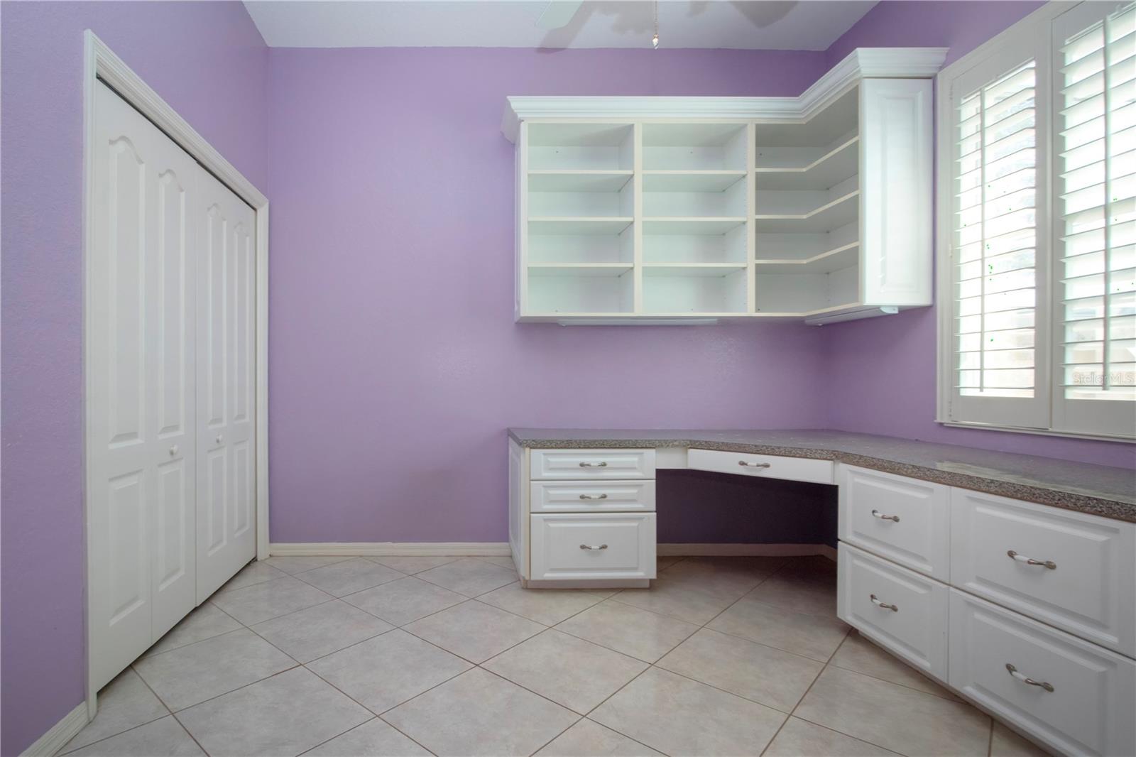 3rd bedroom with custom corner shelving counter space and cabinets