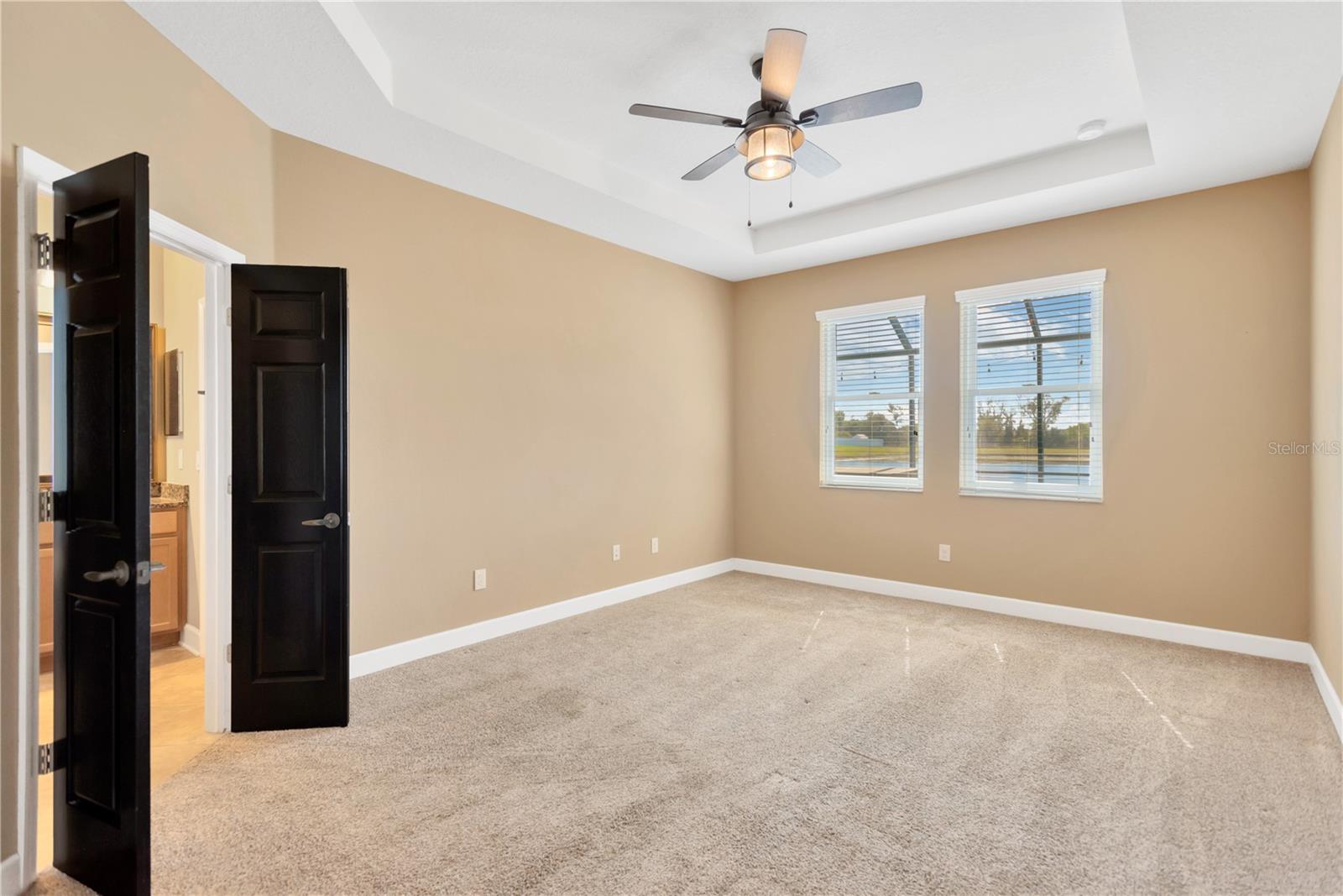 The primary suite has a tray ceiling design and features an en suite bathroom and fabulous walk-in closet behind the double doors.