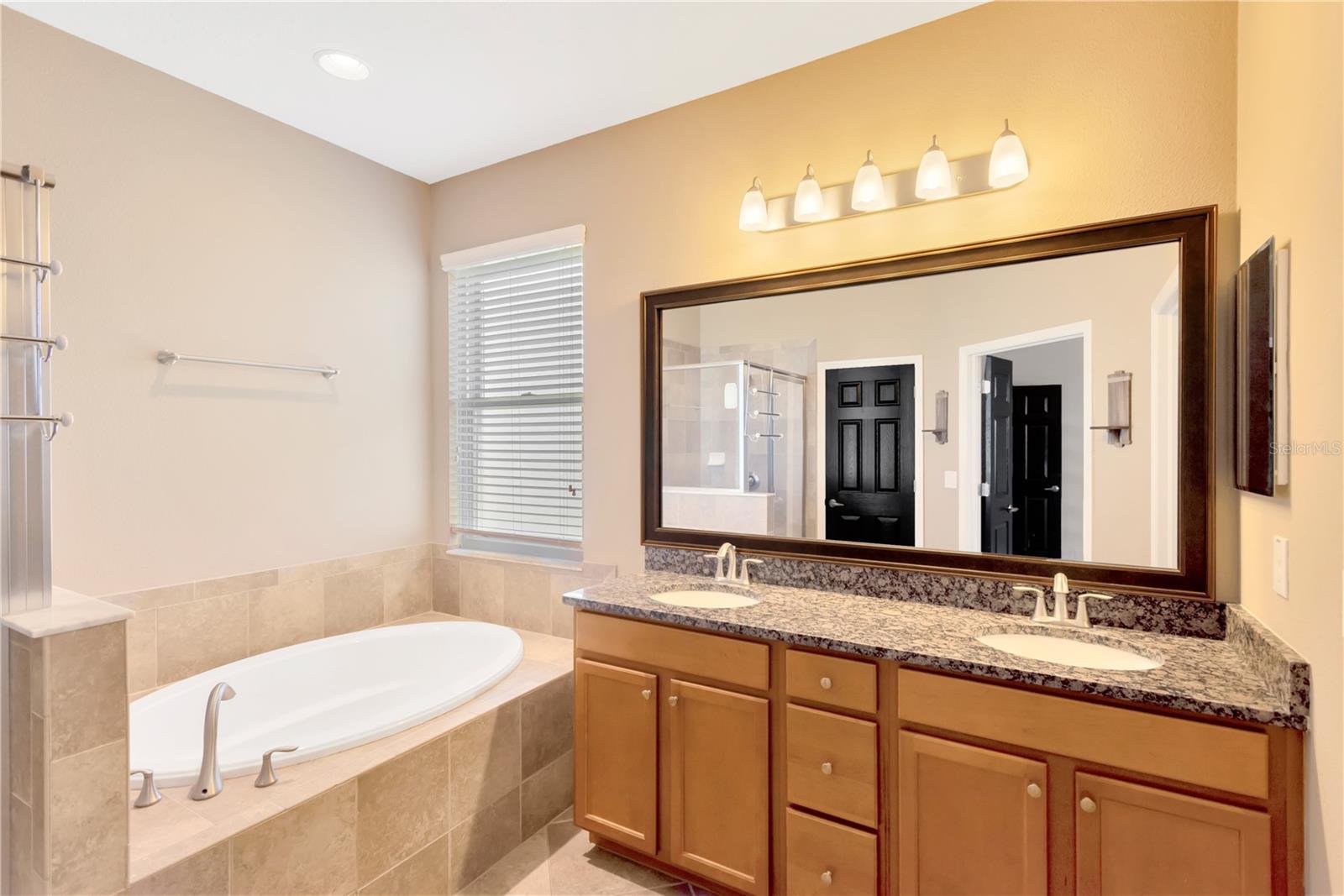 The double vanity in the en suite bathroom has dual sinks mounted under a durable granite surface and has plenty of storage.