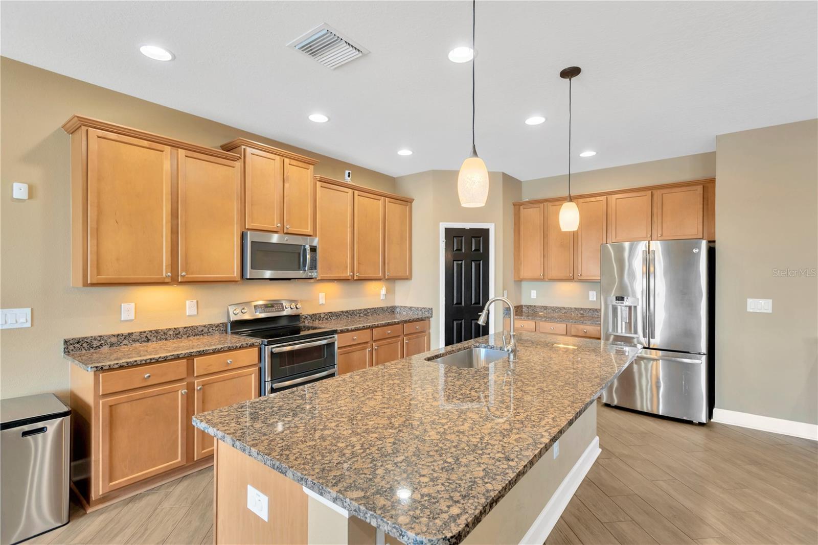 Kitchen features 42" wood cabinets with crown molding, granite countertops, stainless steel appliances including a range with a double oven, a corner walk-in pantry, and a large island.