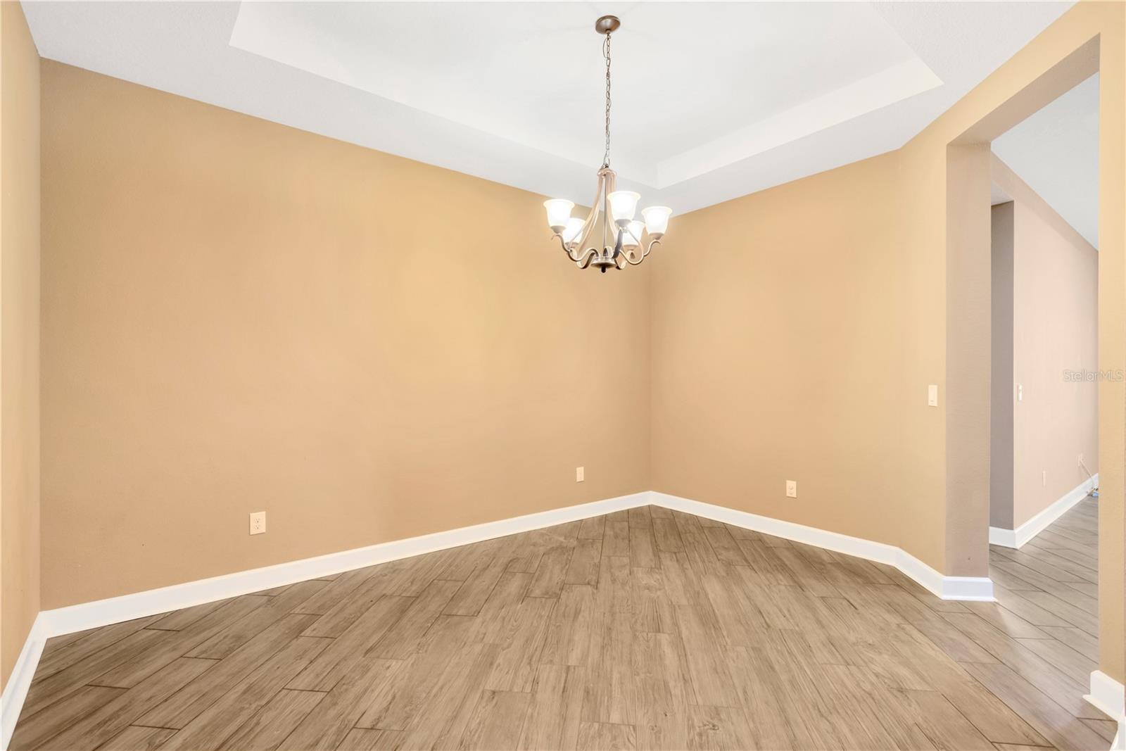 The Dining room boasts soaring ceilings with elegant tray details and newly installed matte porcelain wood-look tile flooring flows through all the living areas and hallways.