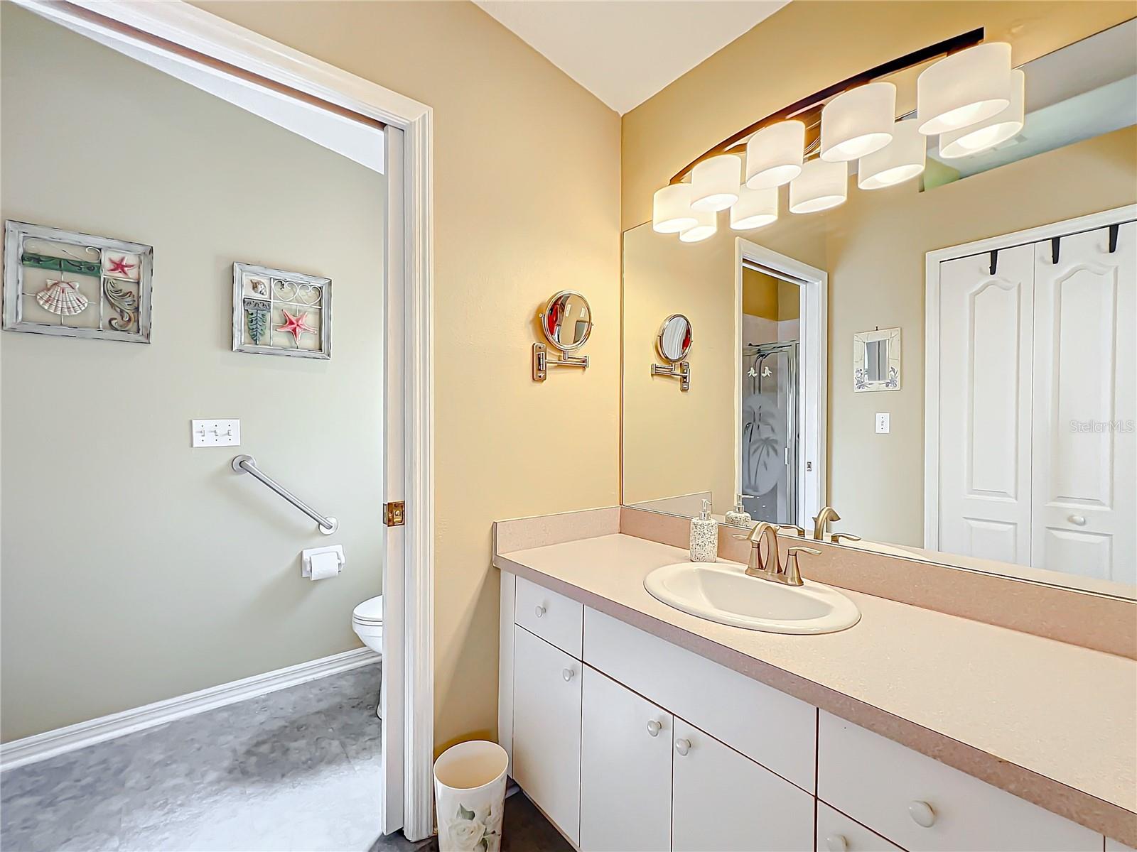 The bathroom has ample counter space with a single sink. Updated lighting. The walk in closet is opposite the sink area.