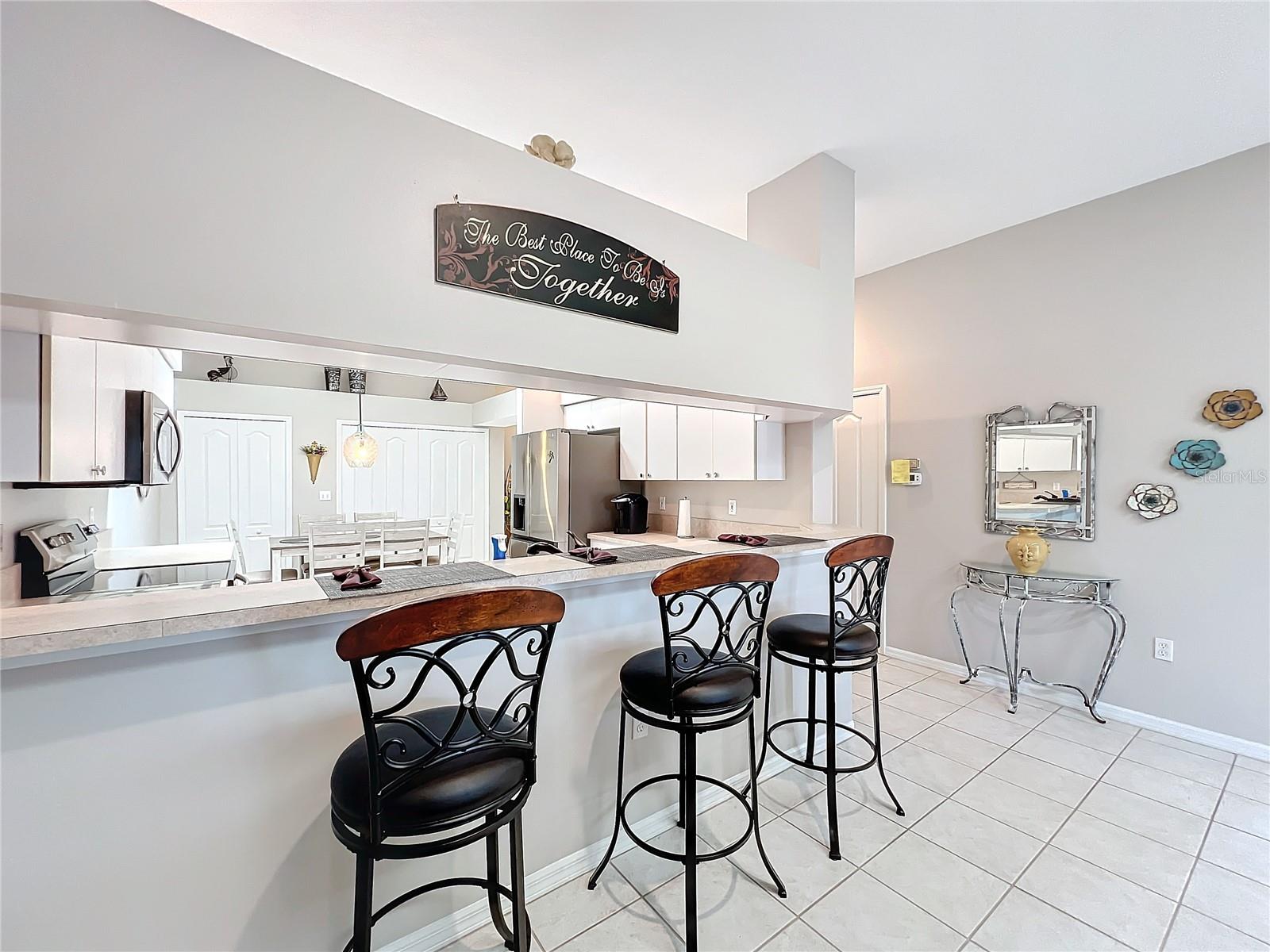 The hallway from the kitchen to the family room area has a closet that can be used for any of your storage needs. This counter base with the stools can be used for those quick meals. Again, the high ceilings and soft colors of home are very calming.