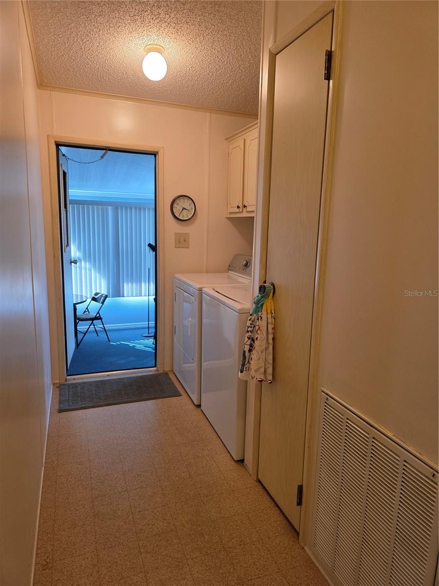 Laundry area with storage closet and cabinetry. Door to Florida room.