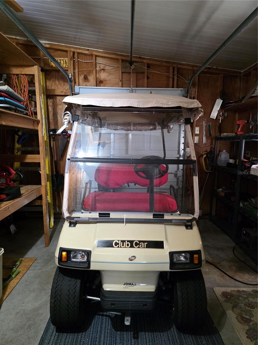 Golf cart garage with shelving and electric garage door opener.