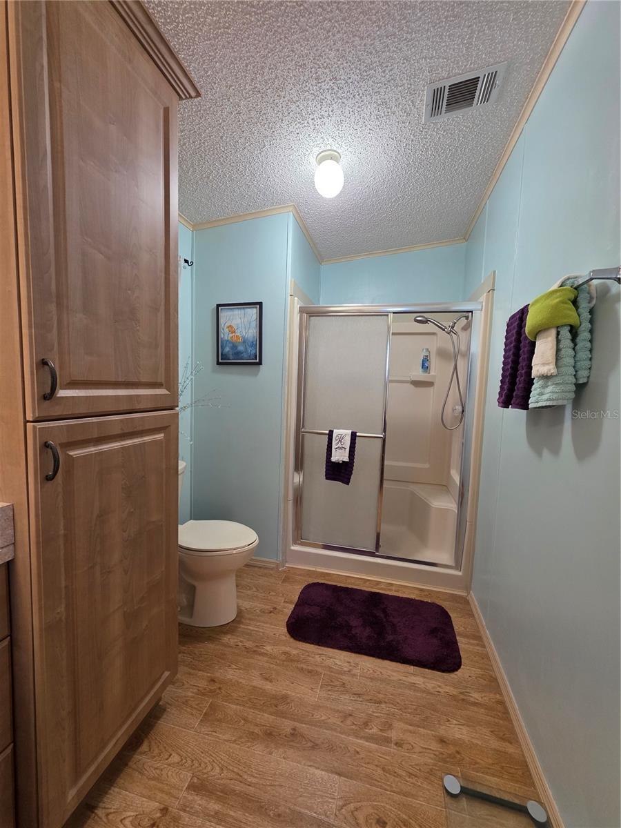 En-suite bathroom with walk-in shower & linen cabinet.