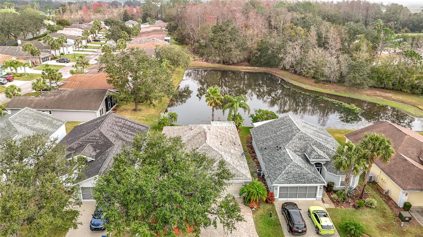 Aerial view of the home overlooking the backyard pond and trees