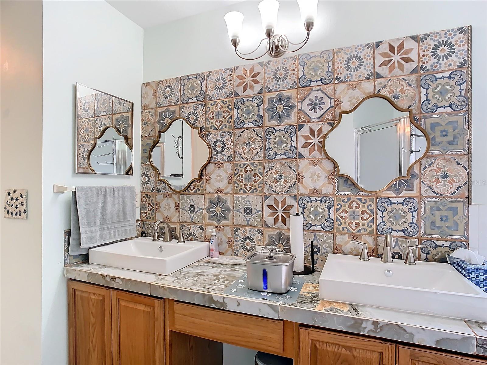 Primary en-suite bathroom with double sink tile vanity complimented by a beautiful tile back splash