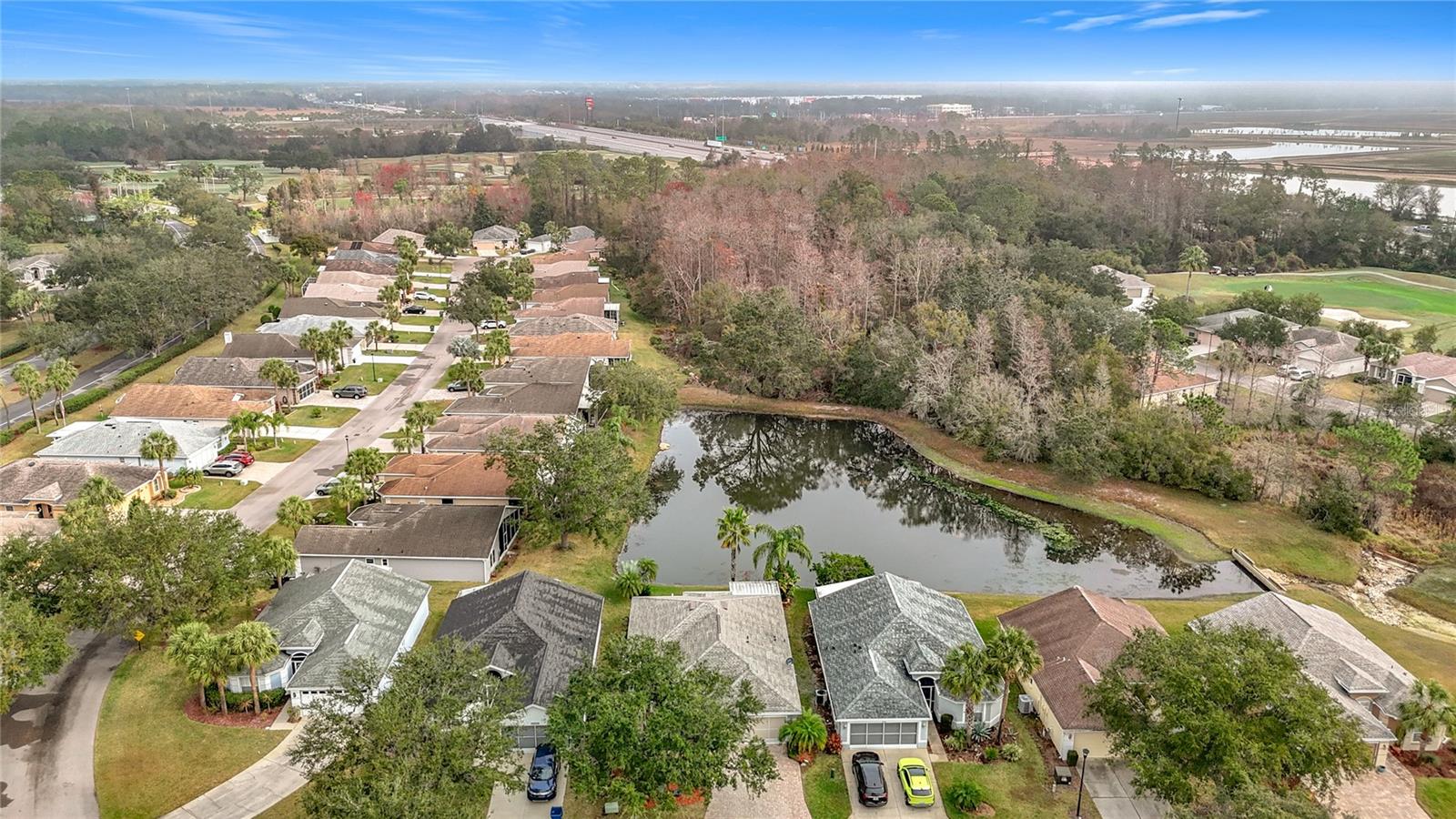 Aerial view of the home overlooking the backyard pond and trees