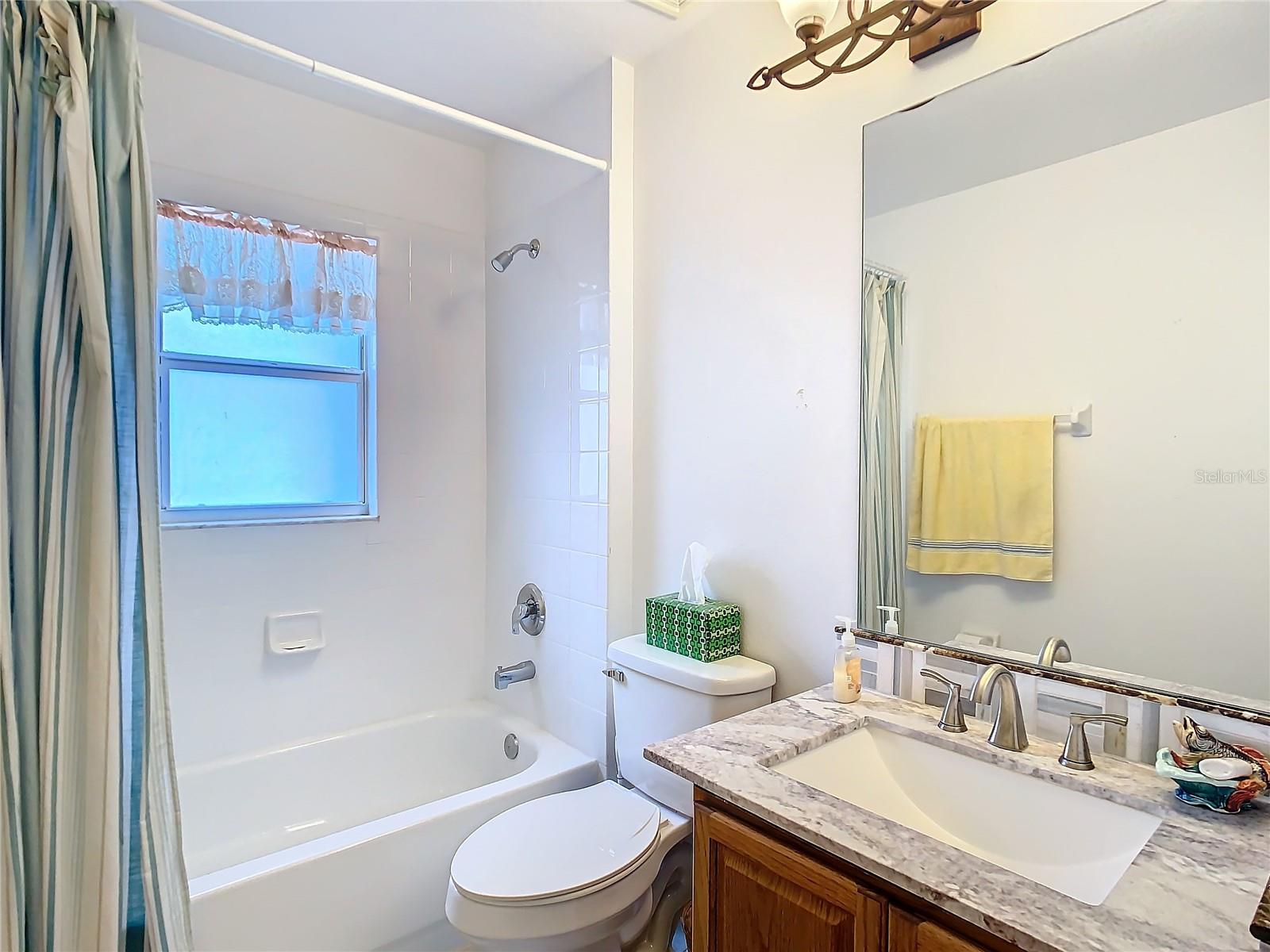 Guest bathroom with granite single vanity and tub with shower