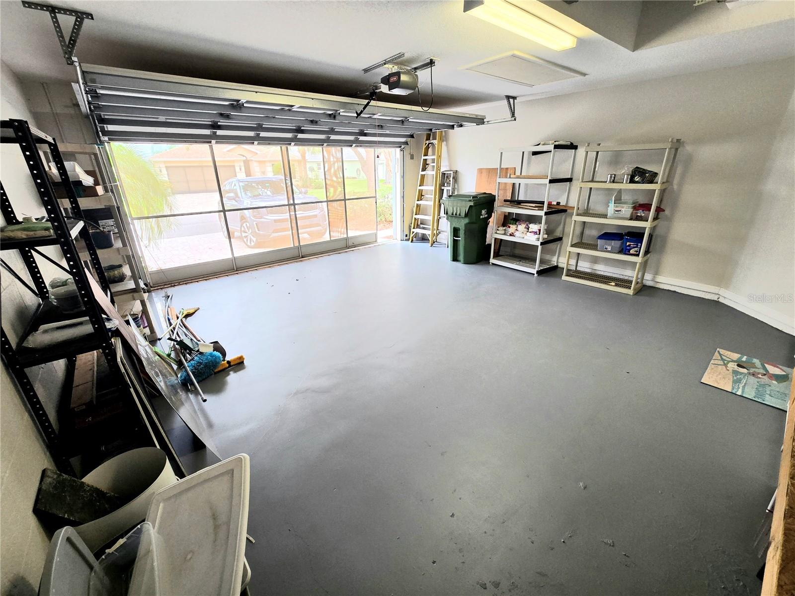 Spacious garage with screen door leading to driveway