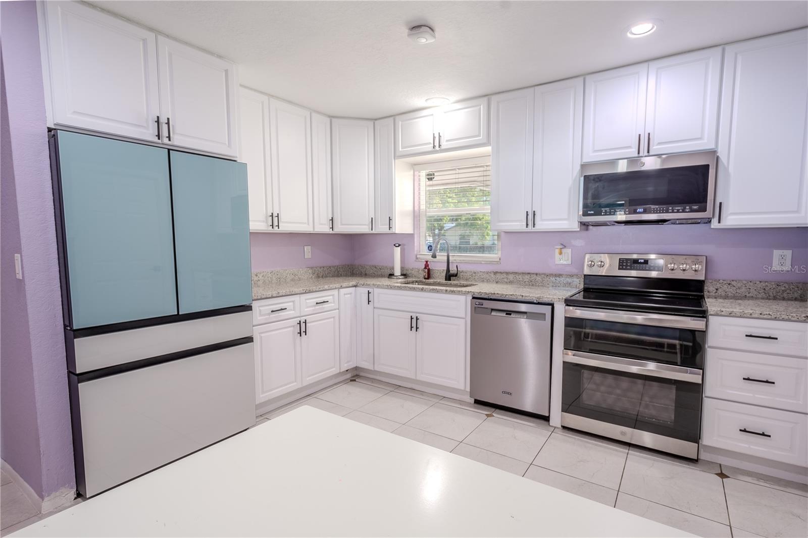 A stainless steel kitchen sink sits beneath the window.