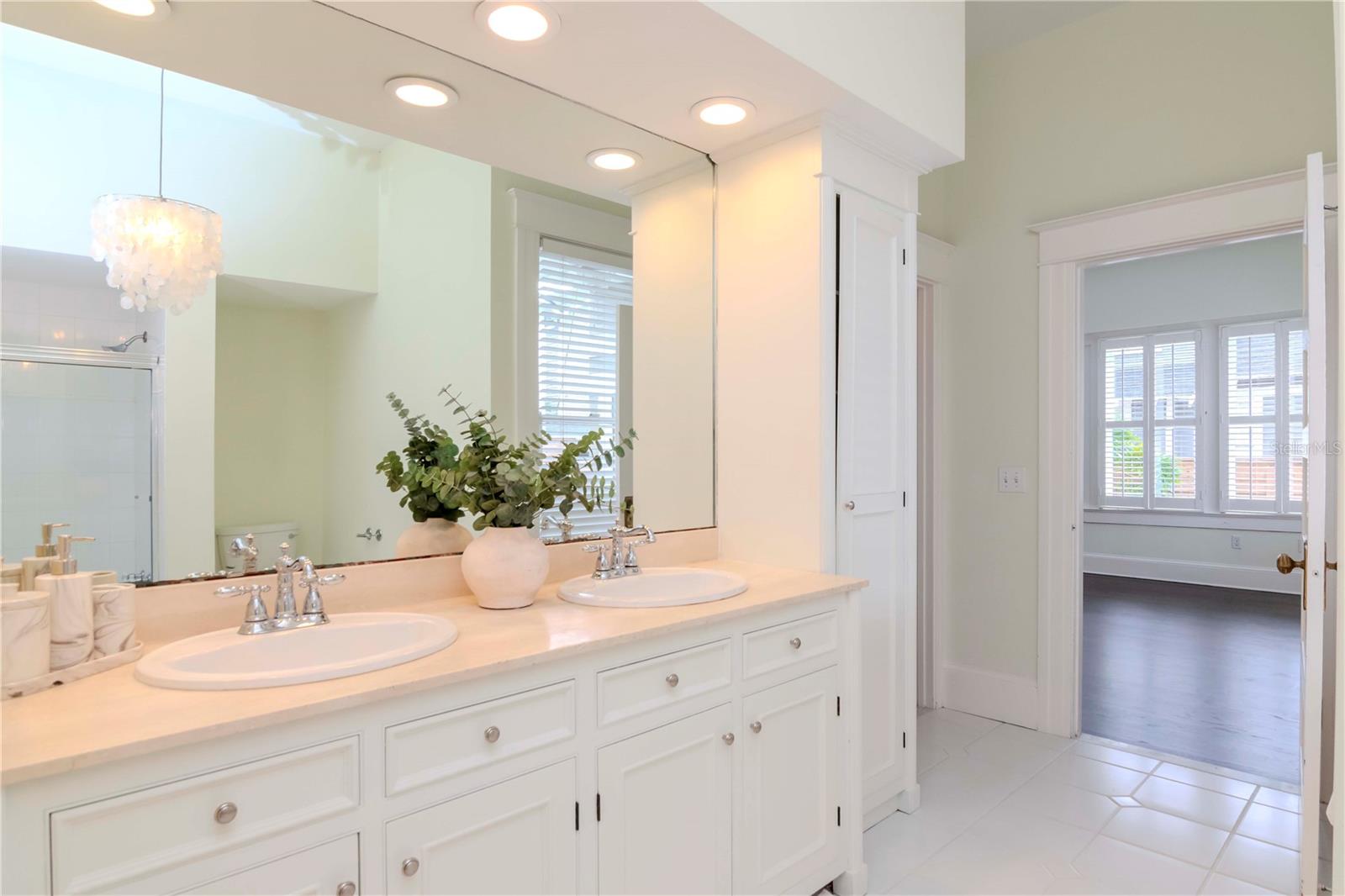 Generously sized, neutral primary bathroom with double vanities and a large walk-in closet.