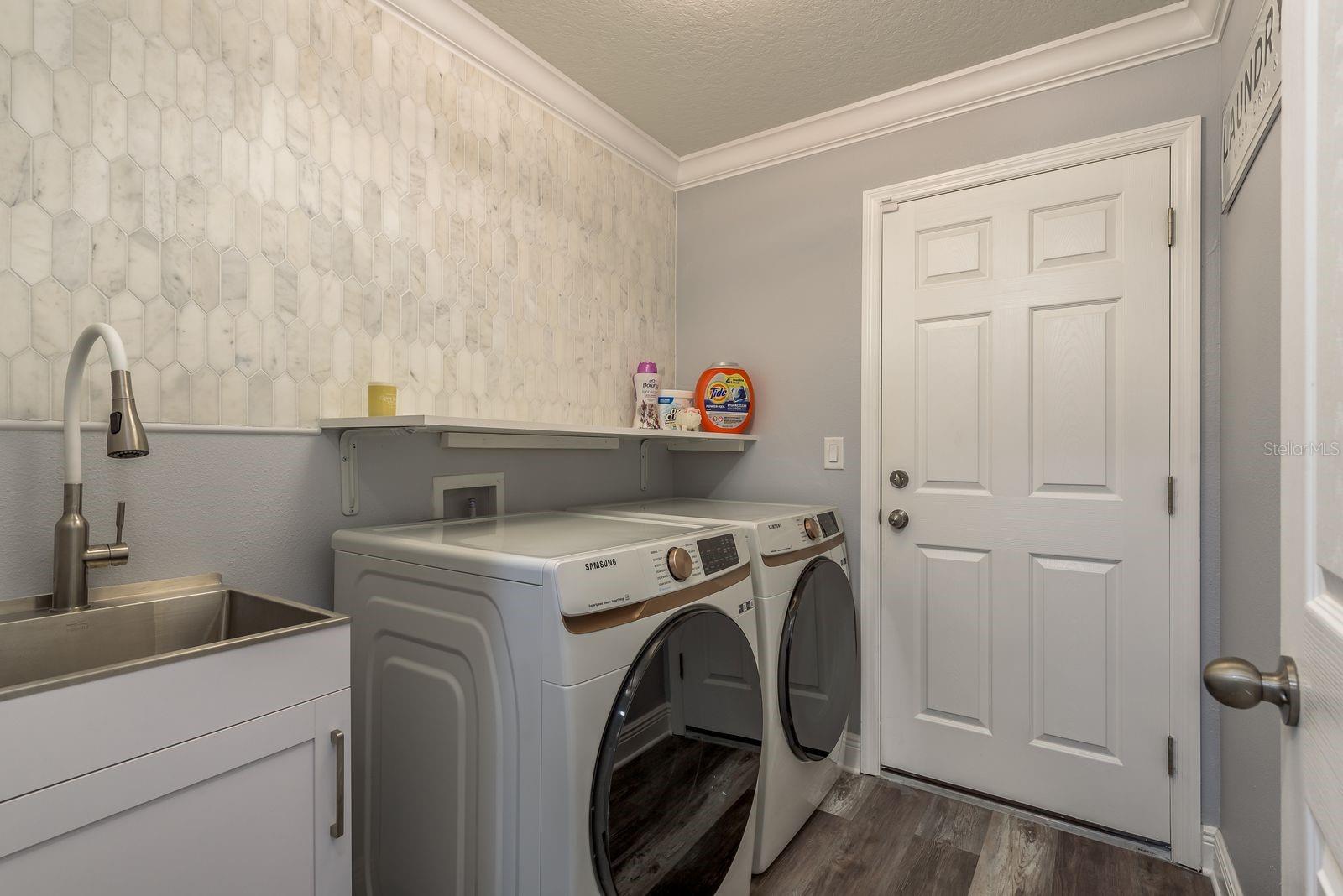 Laundry with beautiful marble accent wall, sink and new machines.