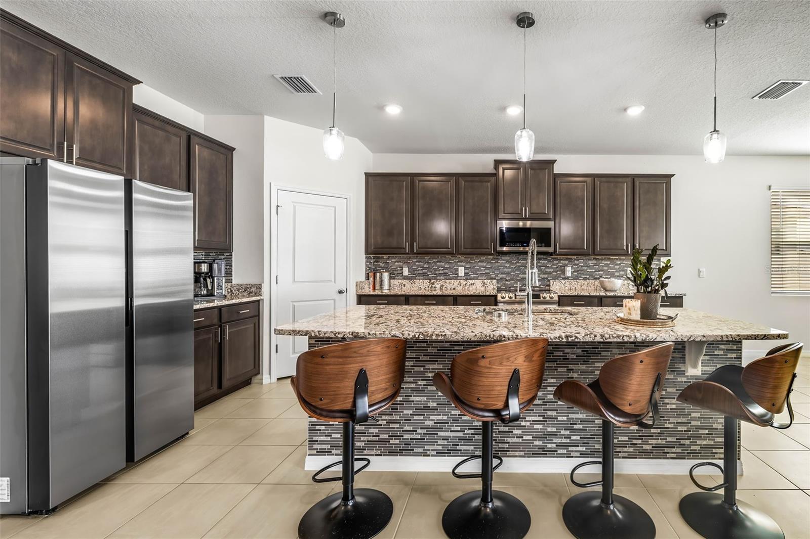 The upgraded kitchen with stainless steel appliances is a cook's dream.  Pendant lighting, backsplash, island seating for 4 & closet pantry.