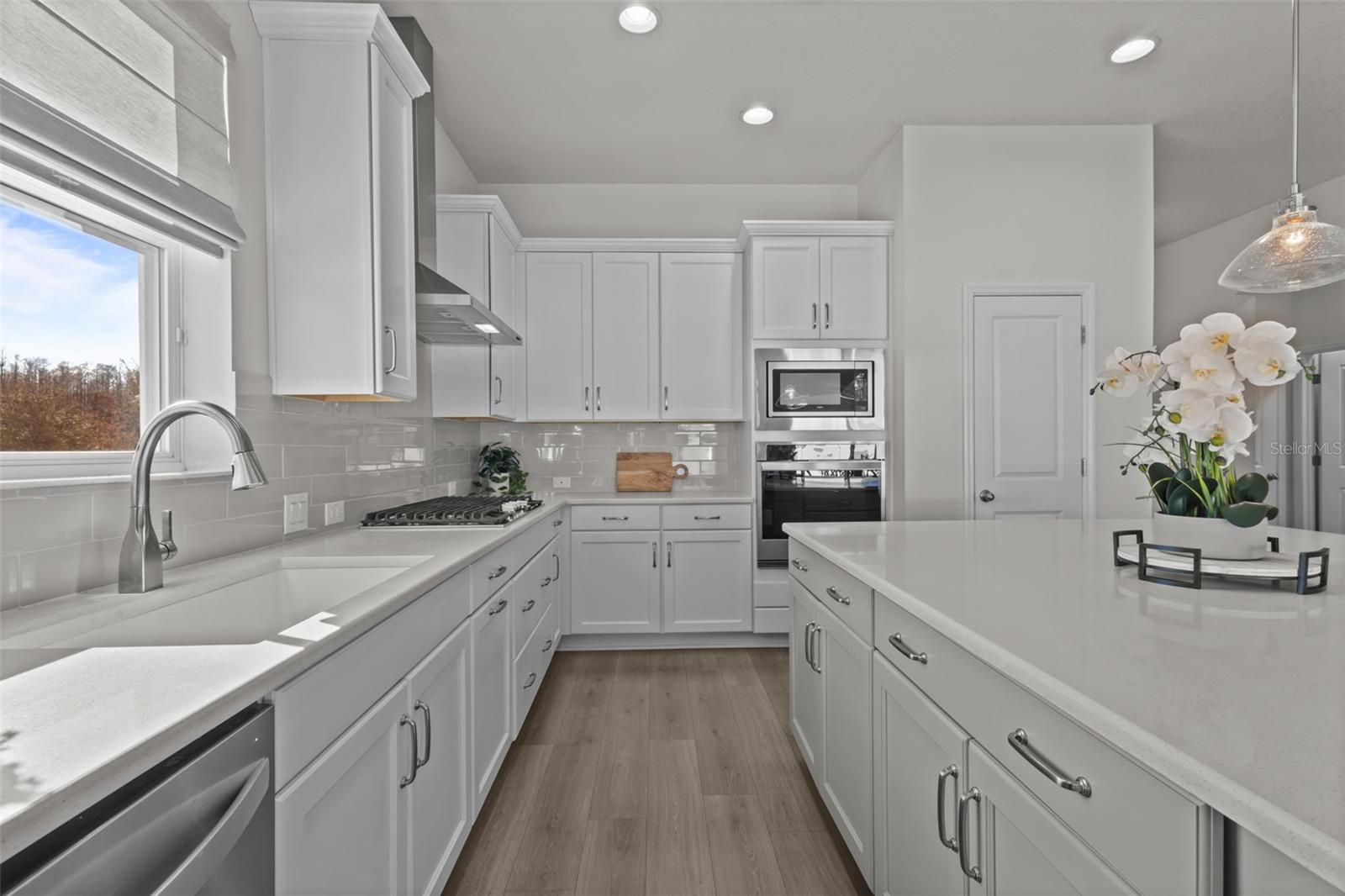 Kitchen -  spacious island, stylish backsplash, built-in stainless steel appliances, and a natural gas range