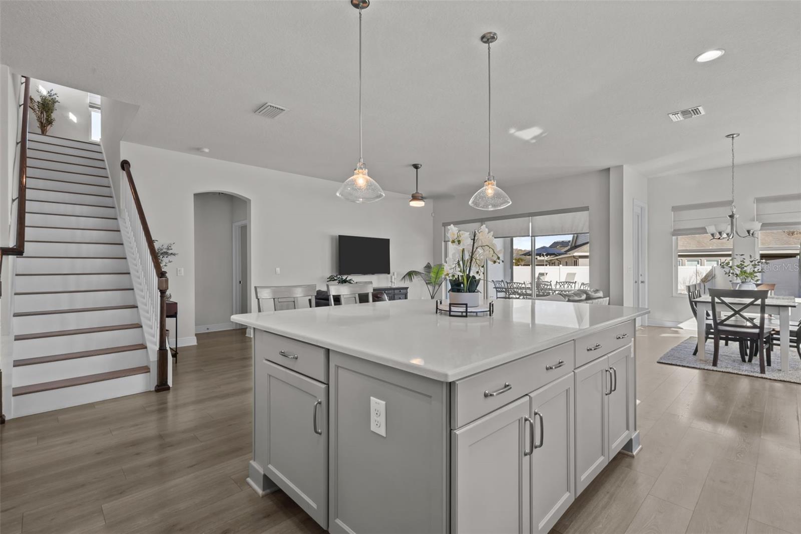 Kitchen view to living space - stairway to left, open look to living, dining, and outside -