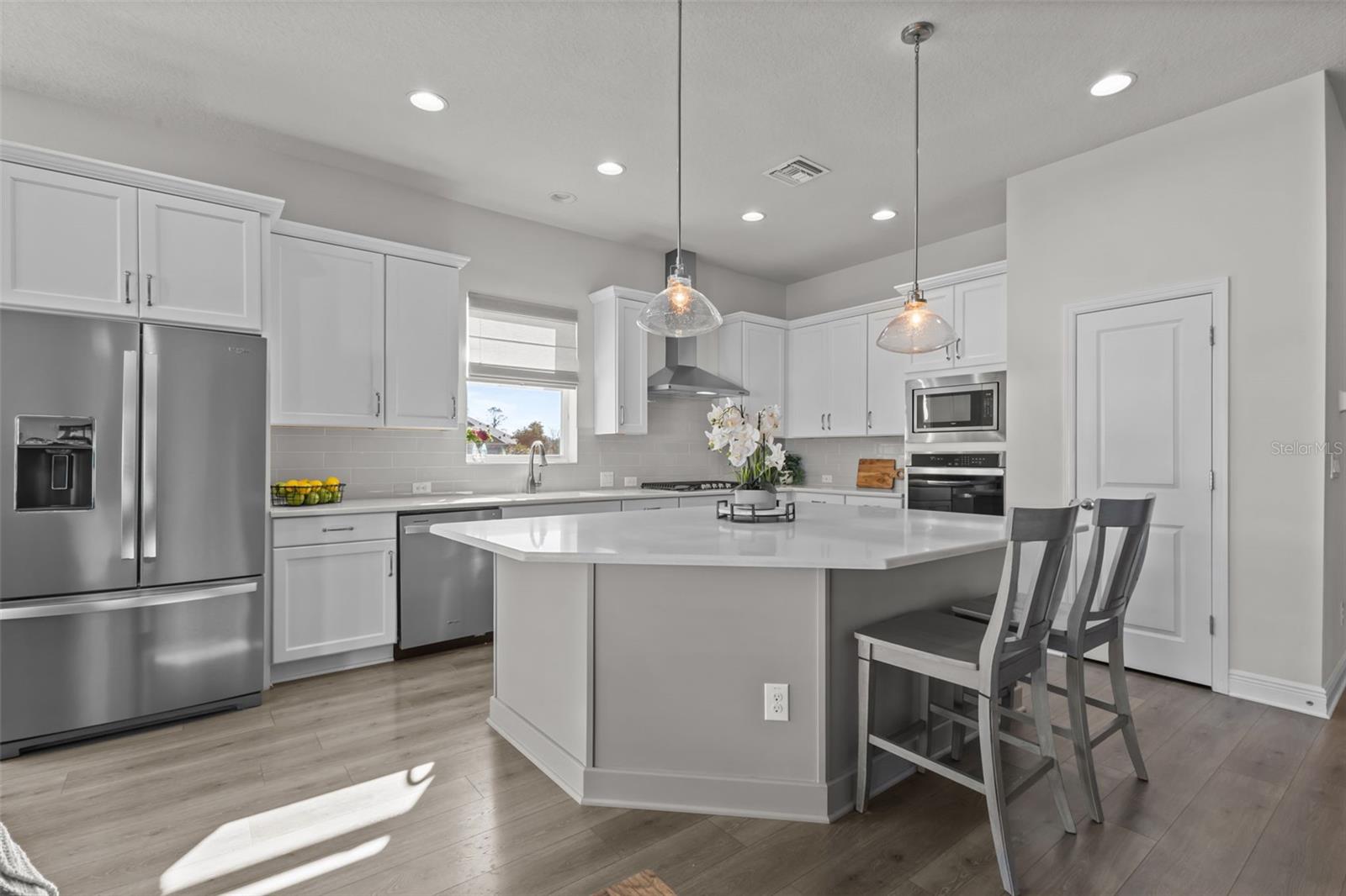 Kitchen - spacious island, stylish backsplash, built-in stainless steel appliances, and a natural gas range