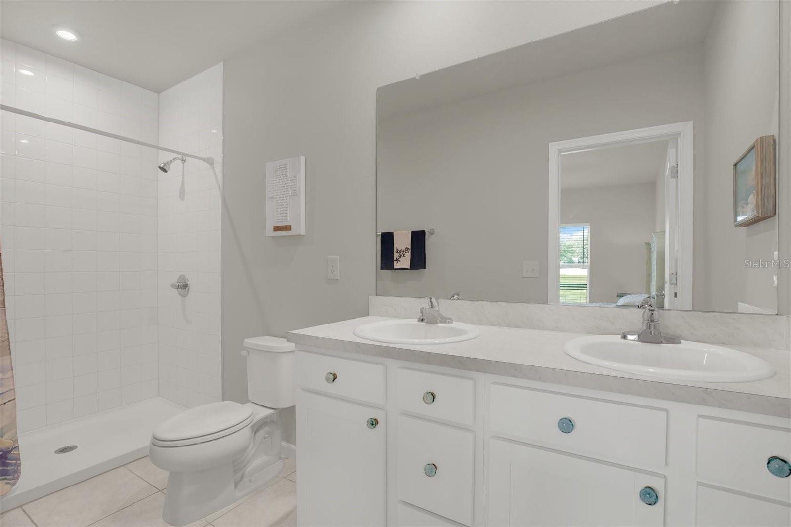 Primary ensuite bathroom features dual sinks and standalone shower