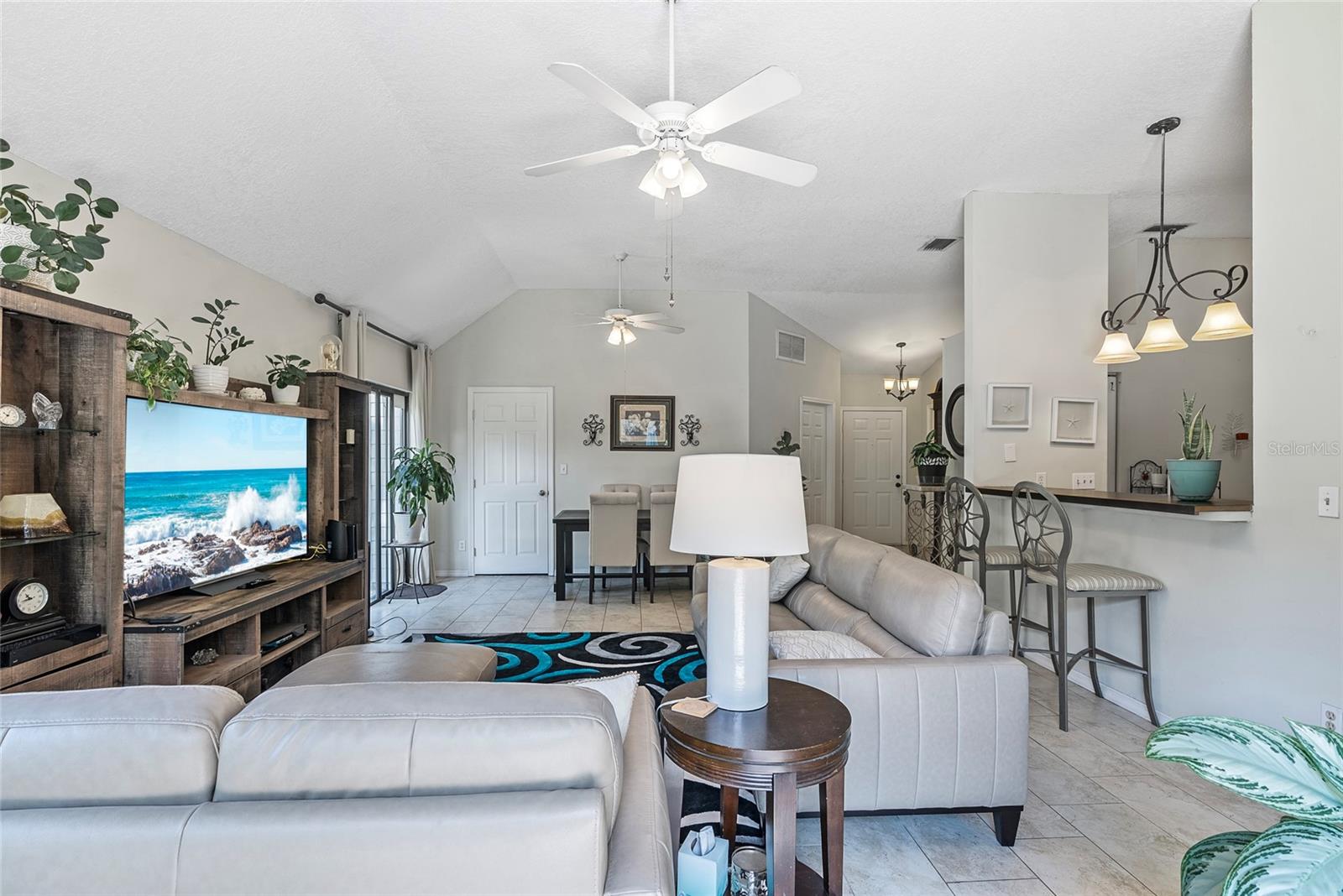 View of the living room, dining room & kitchen.  The door to the laundry closet is the closed door on the left side of the photo next to the sliding glass doors.  The door on the angled wall leads to the 2-car garage and the door to the right of the garage entry is the front door.