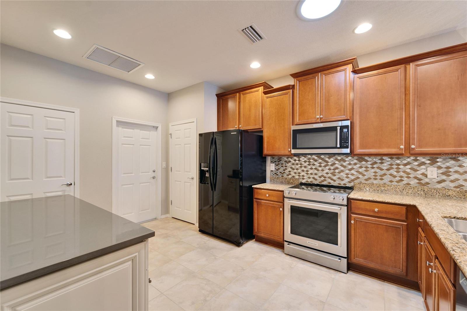 Entering the kitchen with coffee bar on the left. Pantry and entrance to the garage are to t the left of the fridge. Check out the light tube in te ceiling providing additional light.