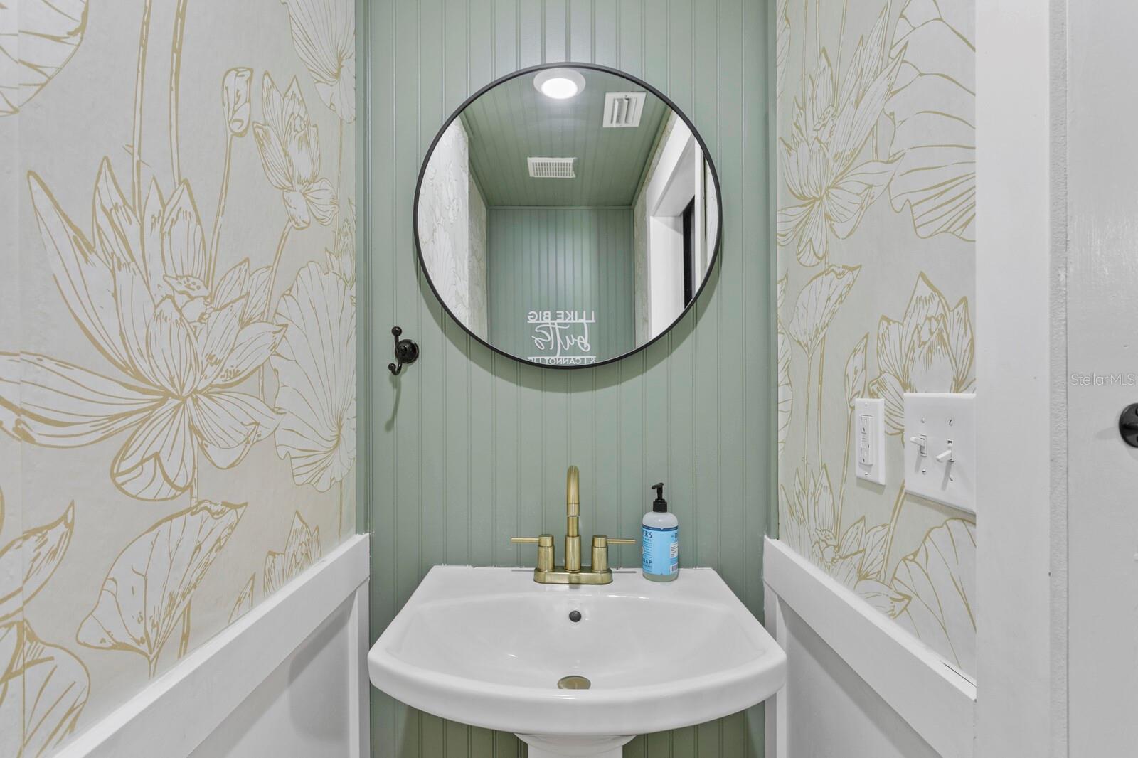 The first floor half bath features a barn door and pedestal sink