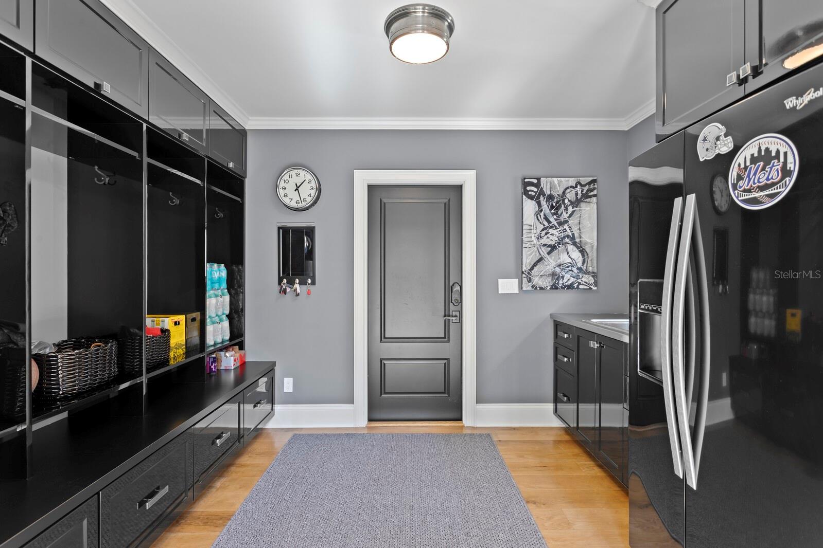 Drop zone with fridge, sink, and cubbies off the garage.