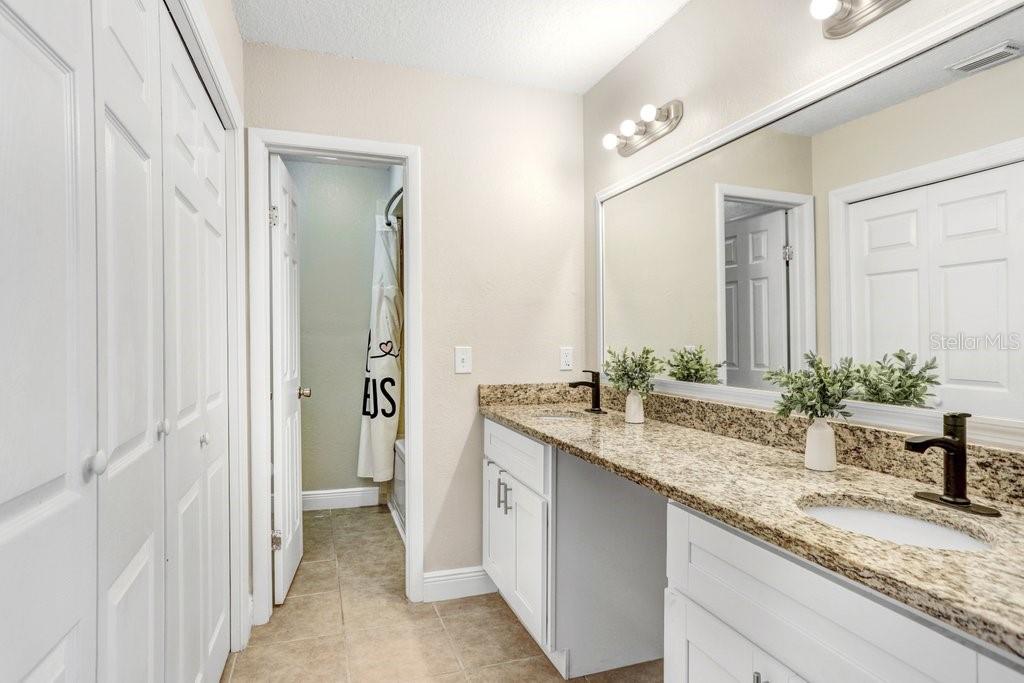 Renovated Primary Bathroom with dual sinks, custom cabinets and granite countertops